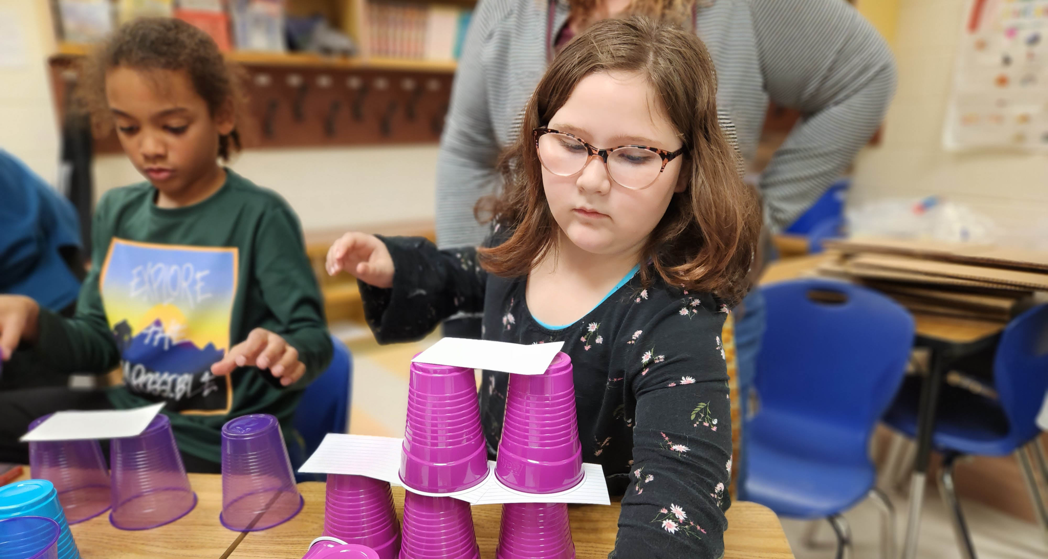 A girl stacking purple plastic cups in class
