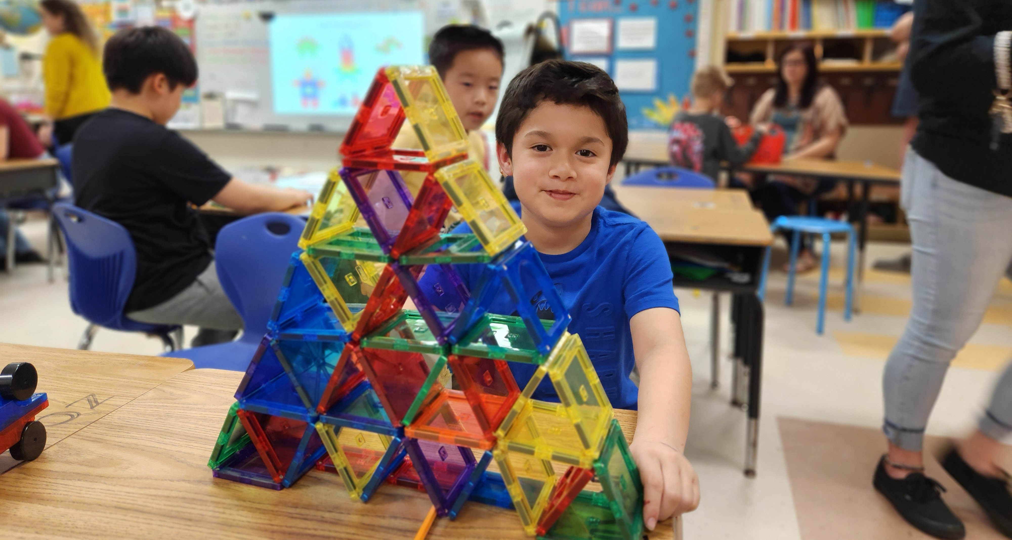 A student sitting in front of a structure made of plastic pieces