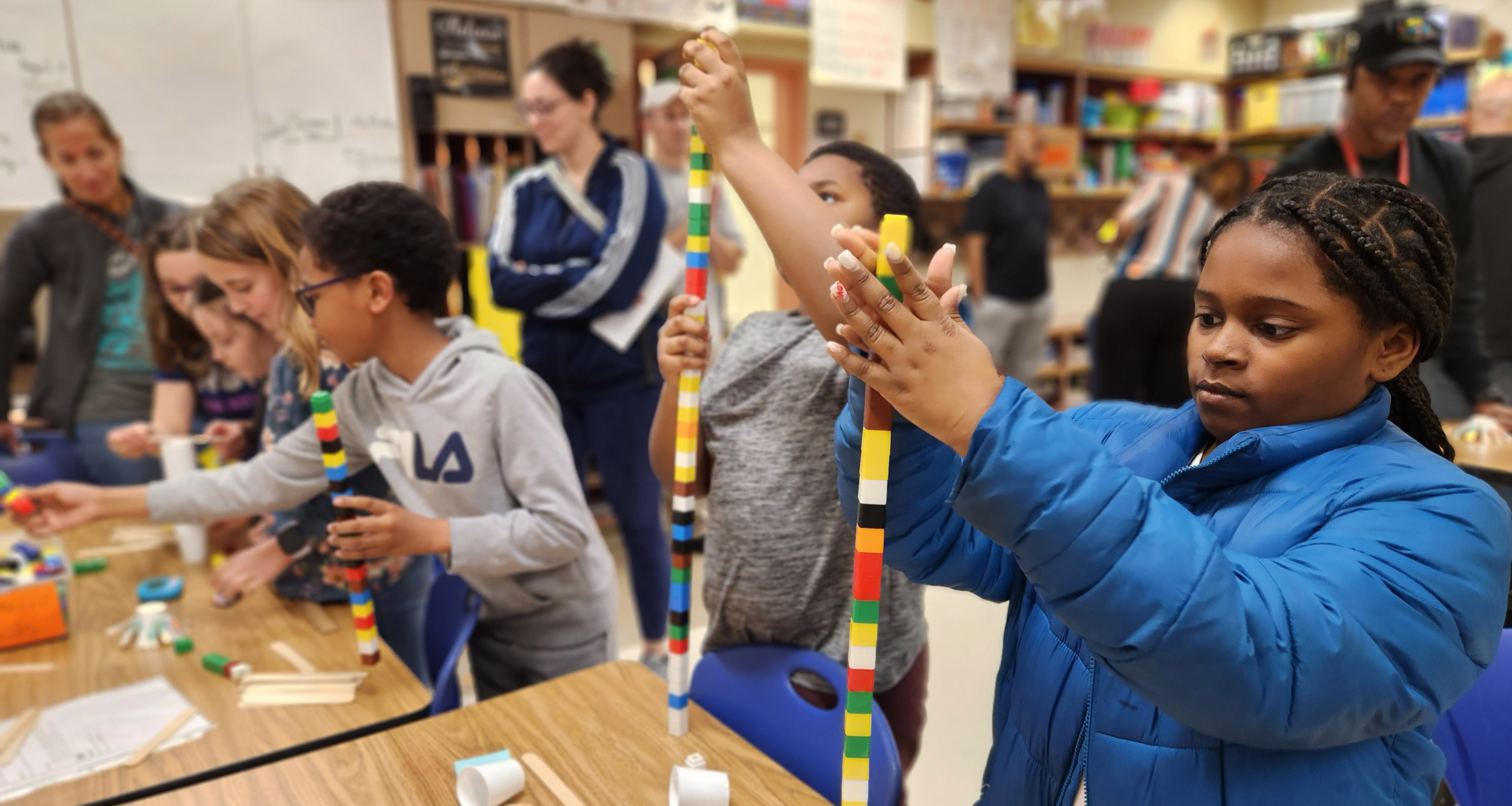 A group of students stacking cubes very high