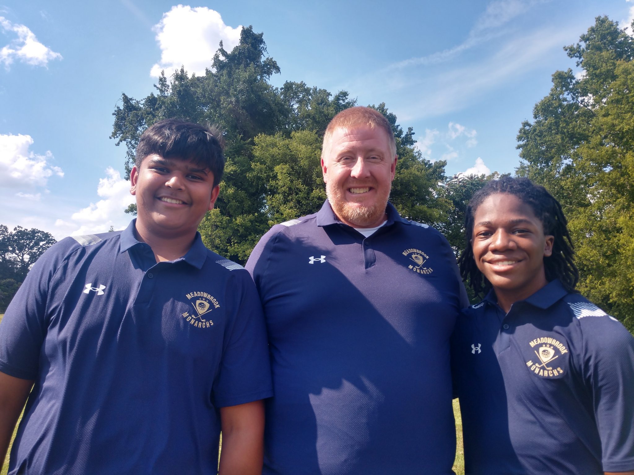 Two golf team members and their coach pose for a photo