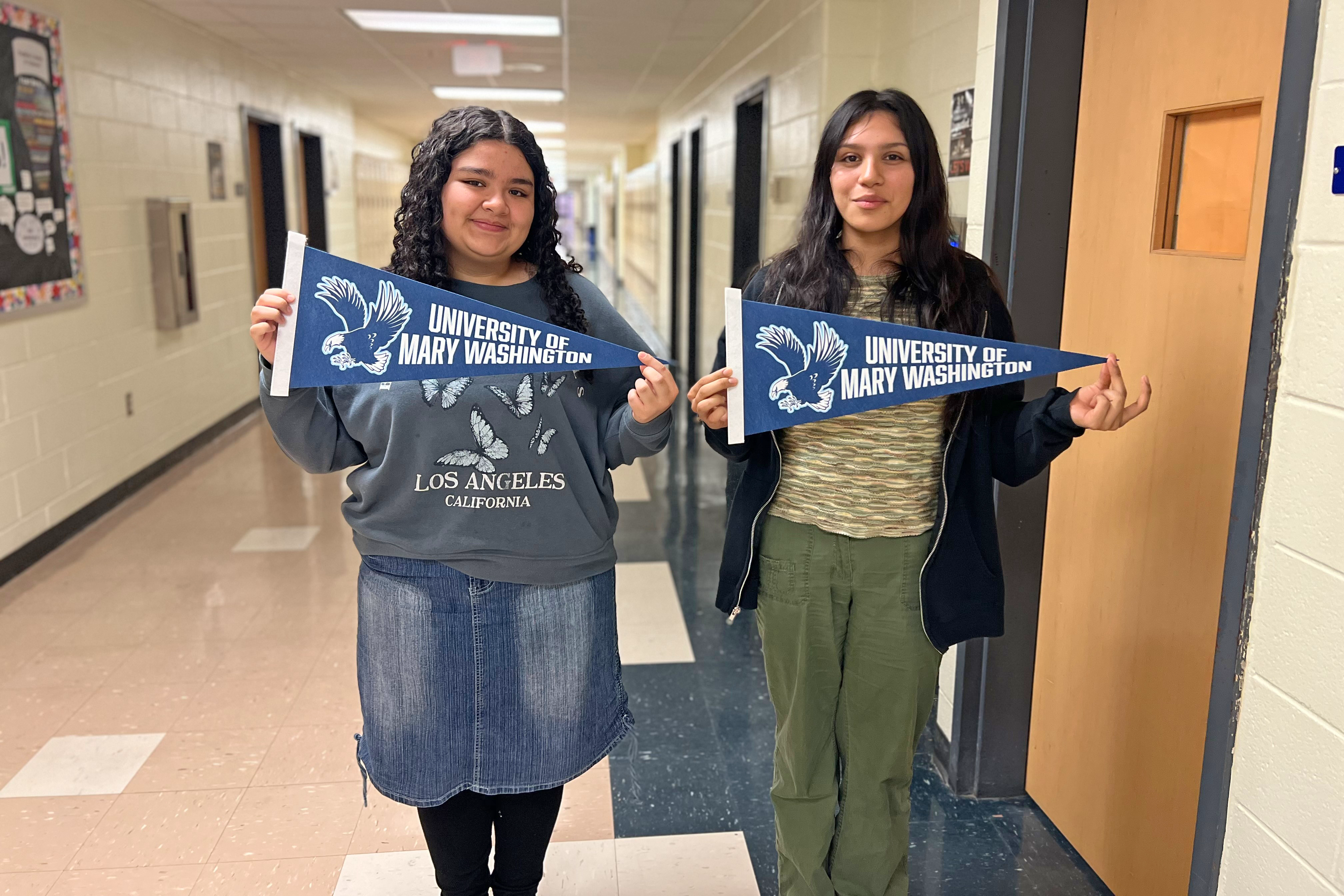 Two girls holding up college pennant flags