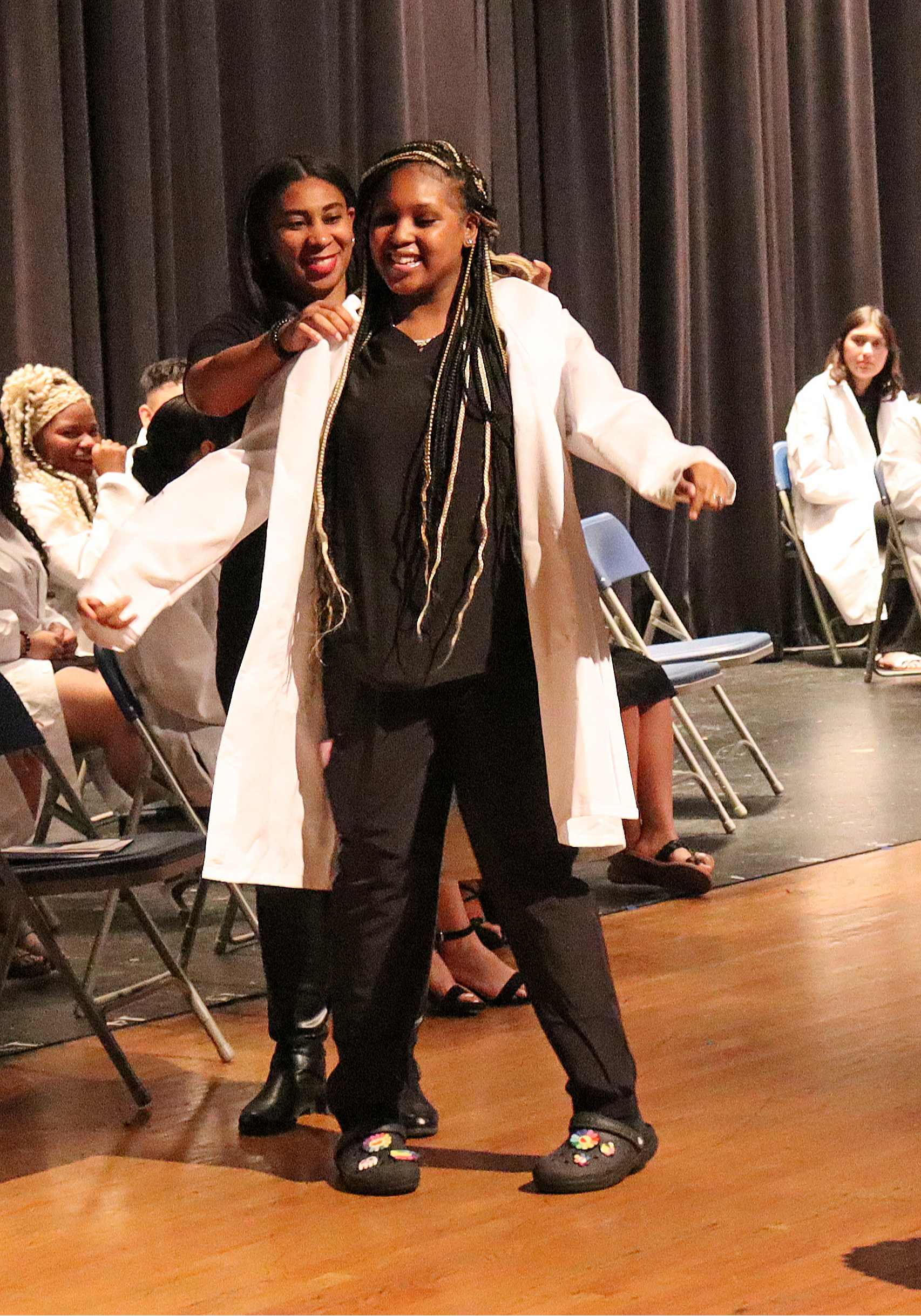 A teacher putting a white coat on a student