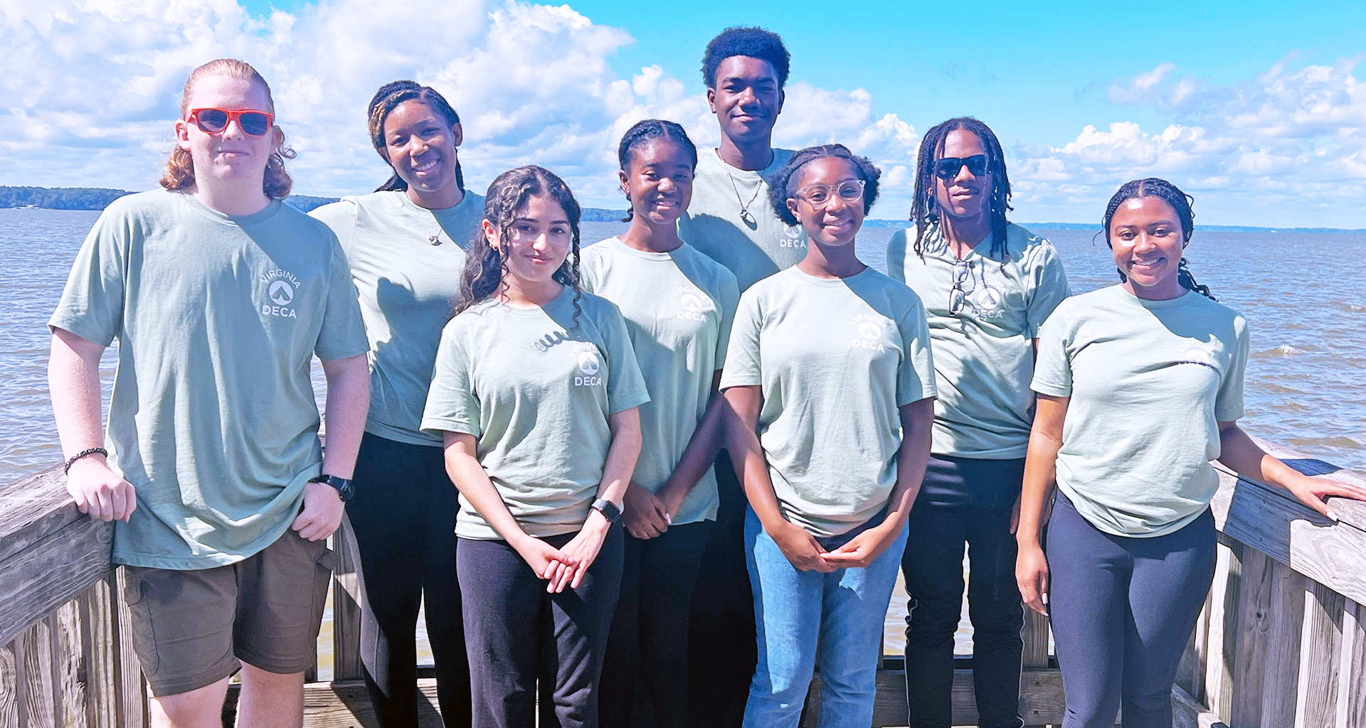 group of students pose on a dock