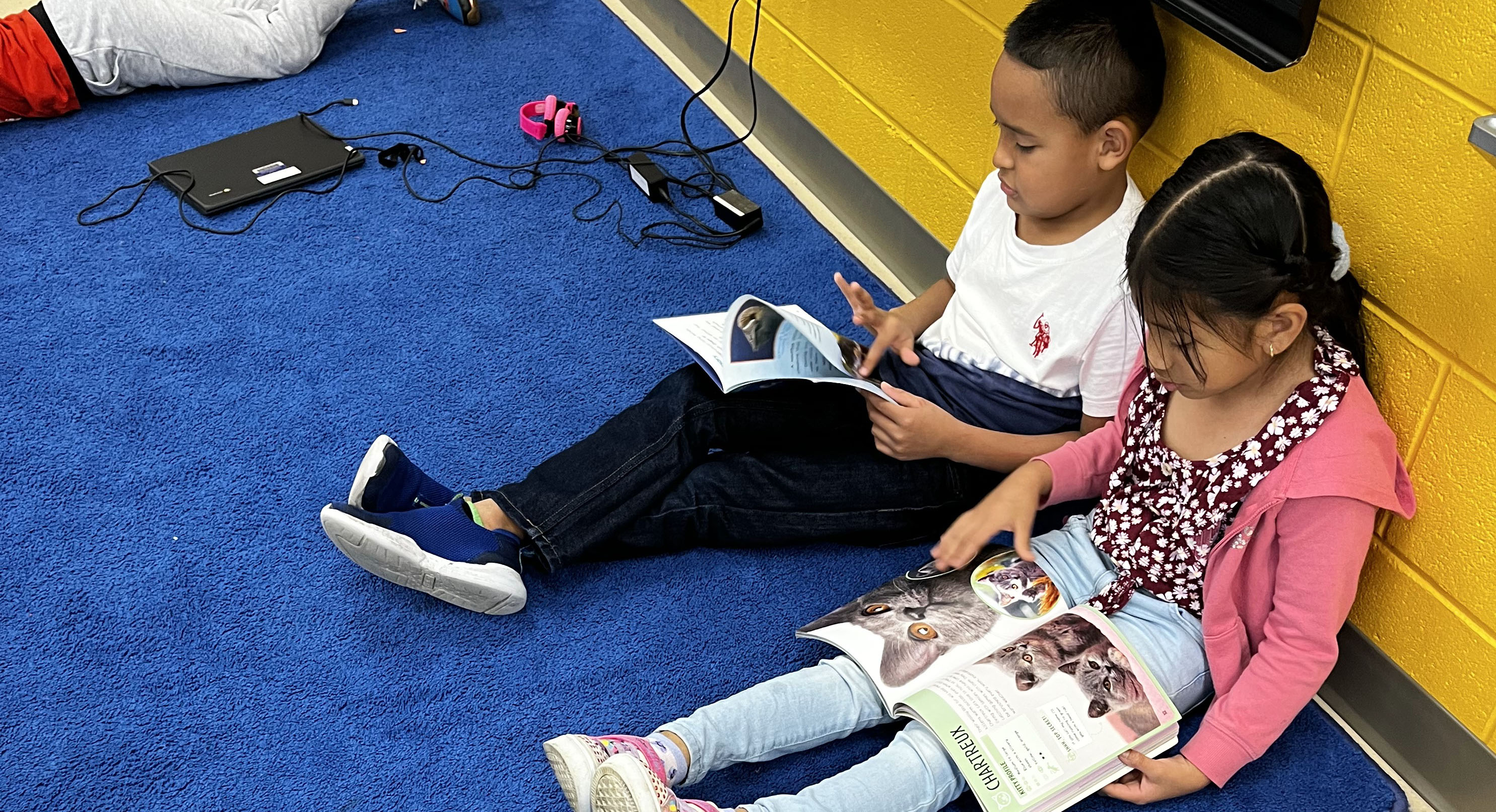 Two students reading books on the carpet