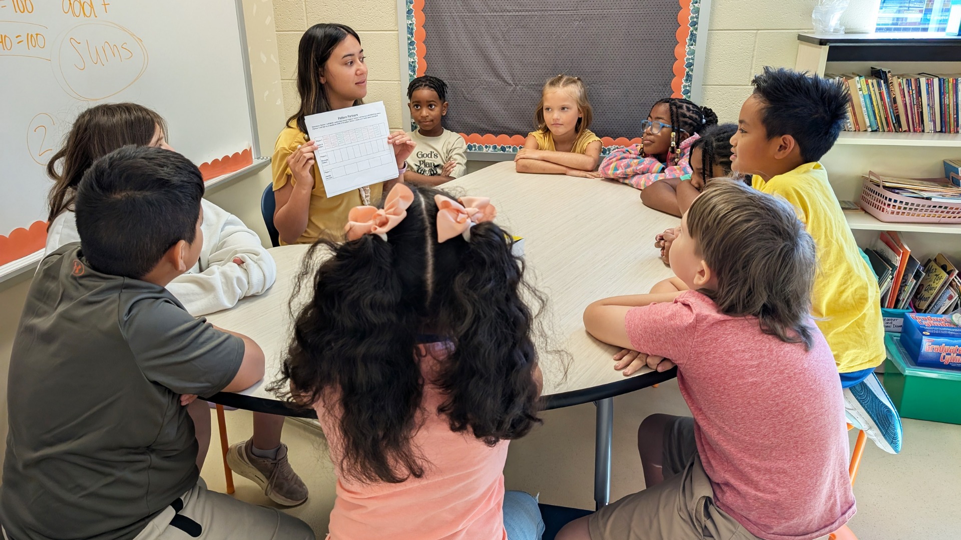 Students working with teacher at a table.
