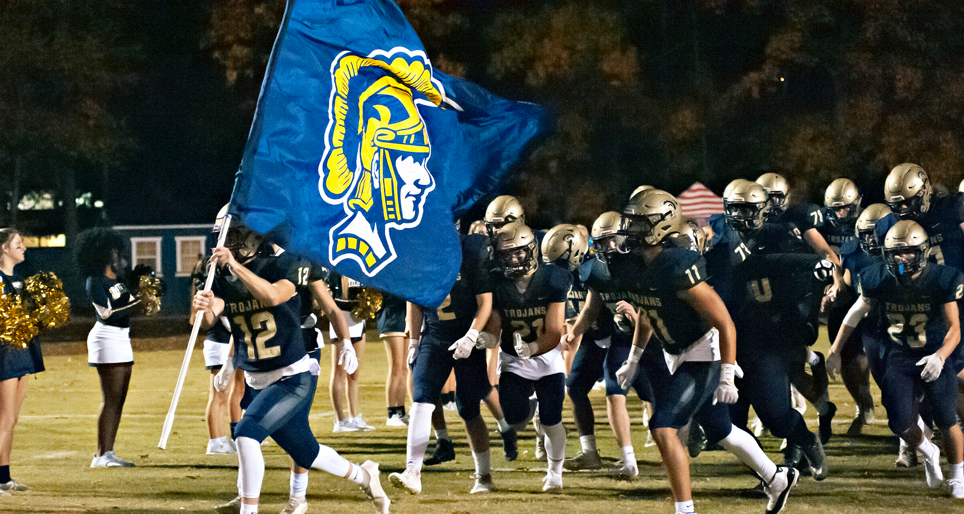Football team run on to the field with a flag