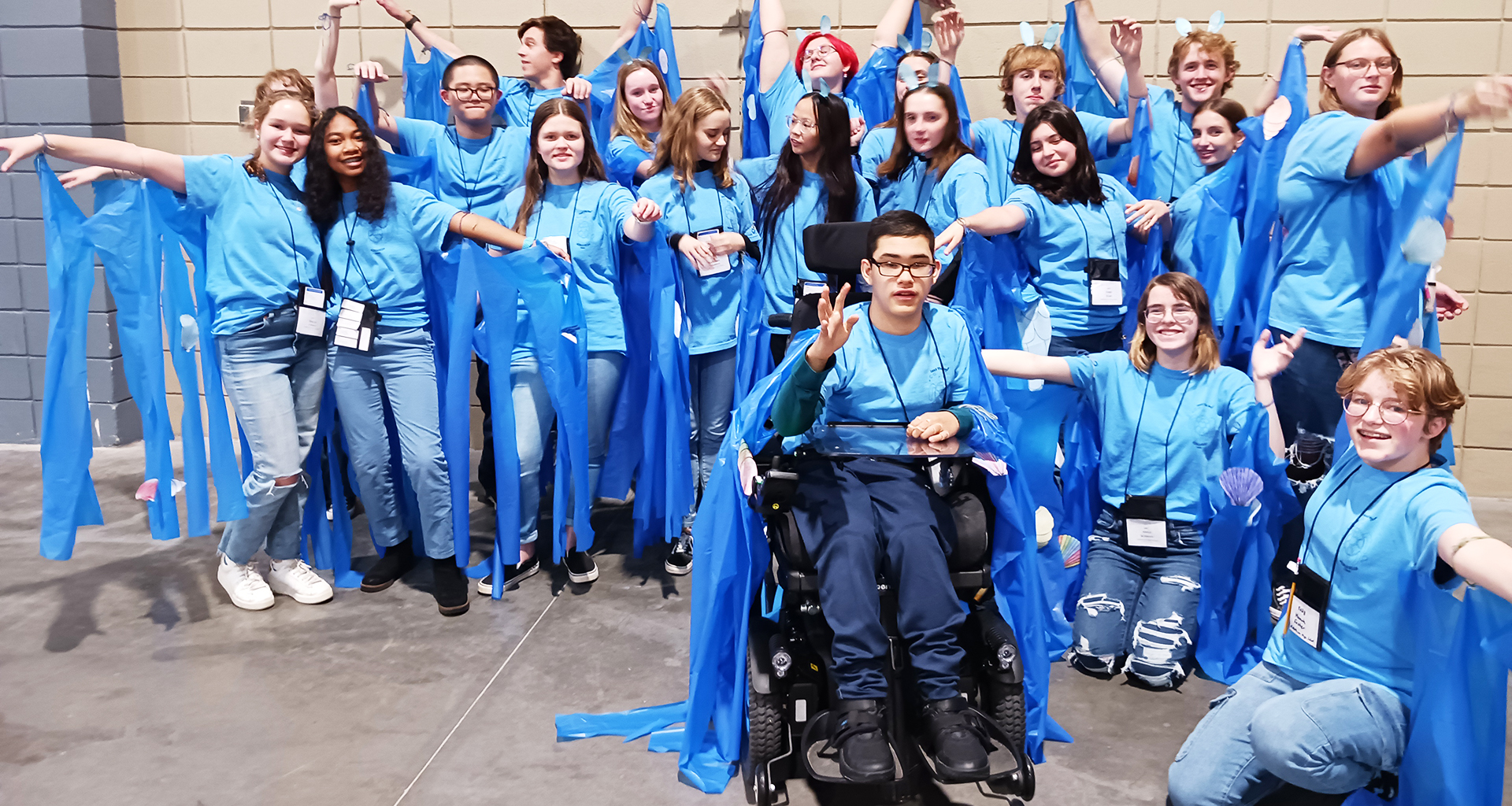 Large group of students dressed in blue pose for a photo