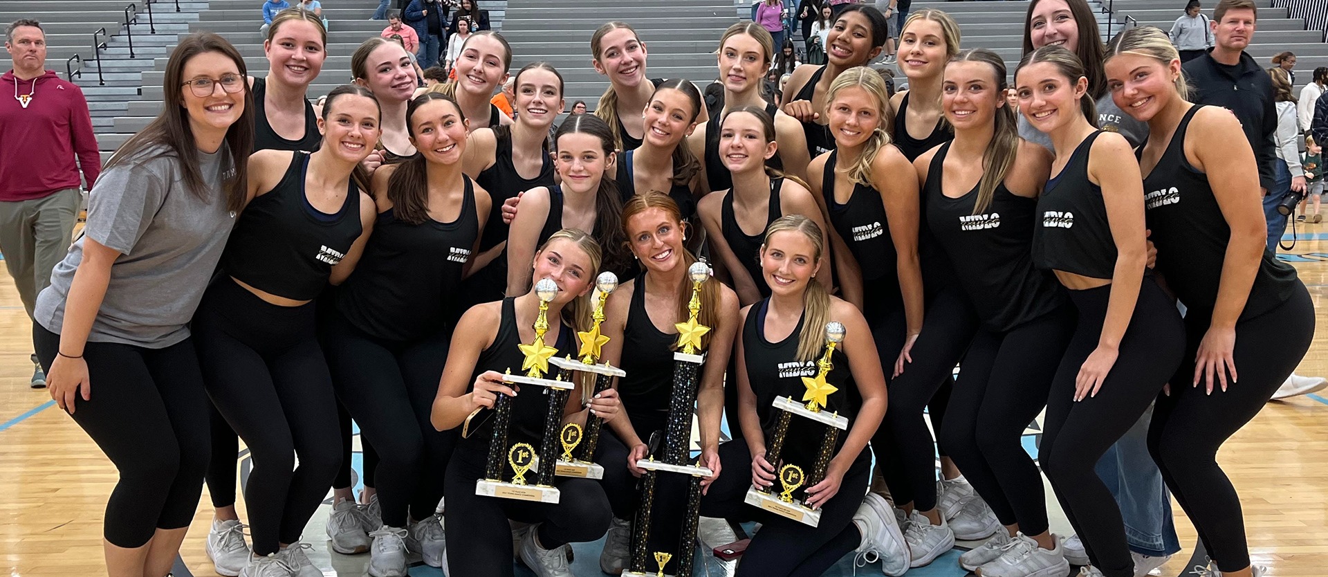 Cheerleading team holding up their trophy and posing for a photo