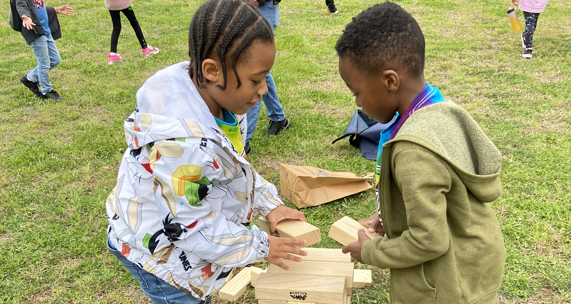 Two students playing with wooden blocks outside