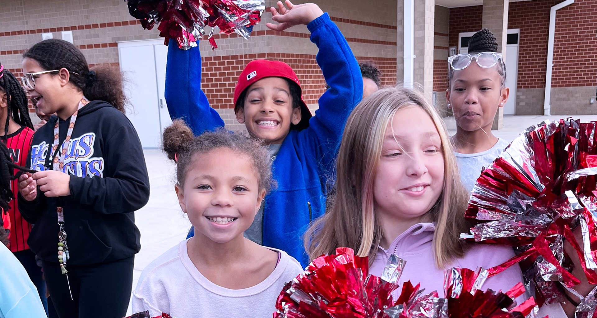 Students with pompoms outside smiling for the camera.