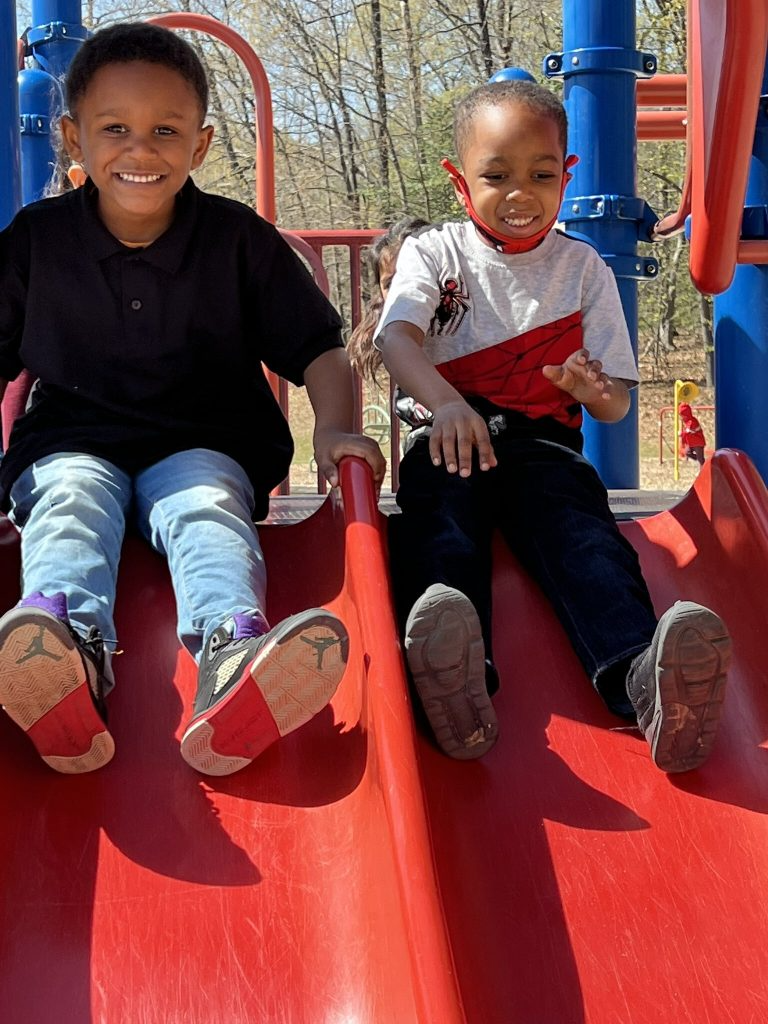 Two students getting ready to go down the slide