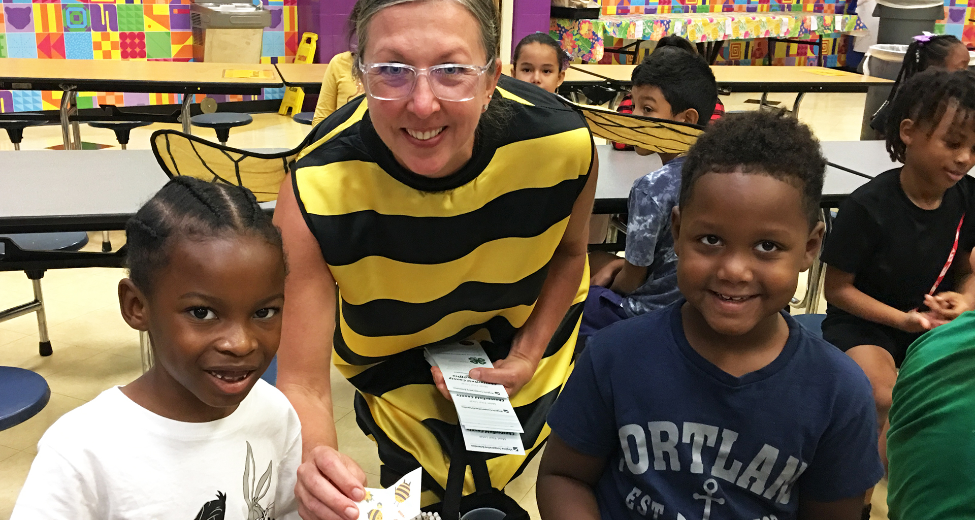 Two students and a special guest dressed as a bee pose for a photo.