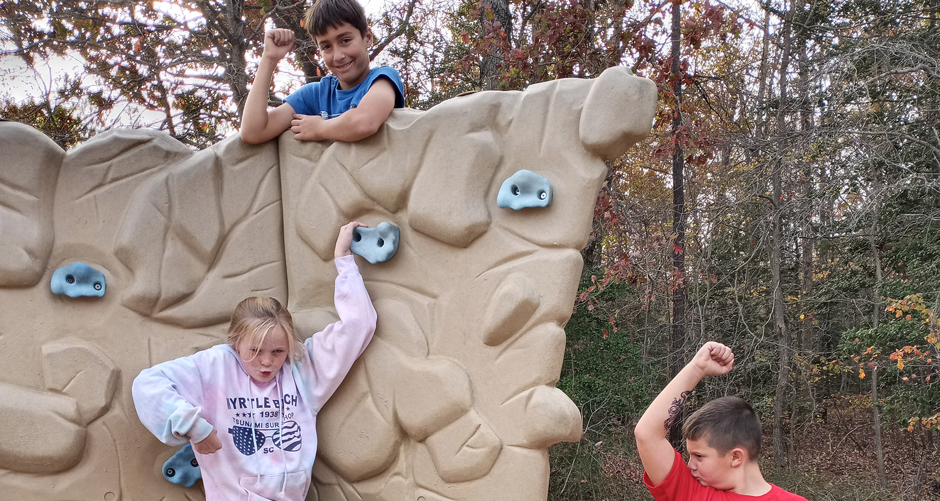 Three students acting silly on a climb wall.