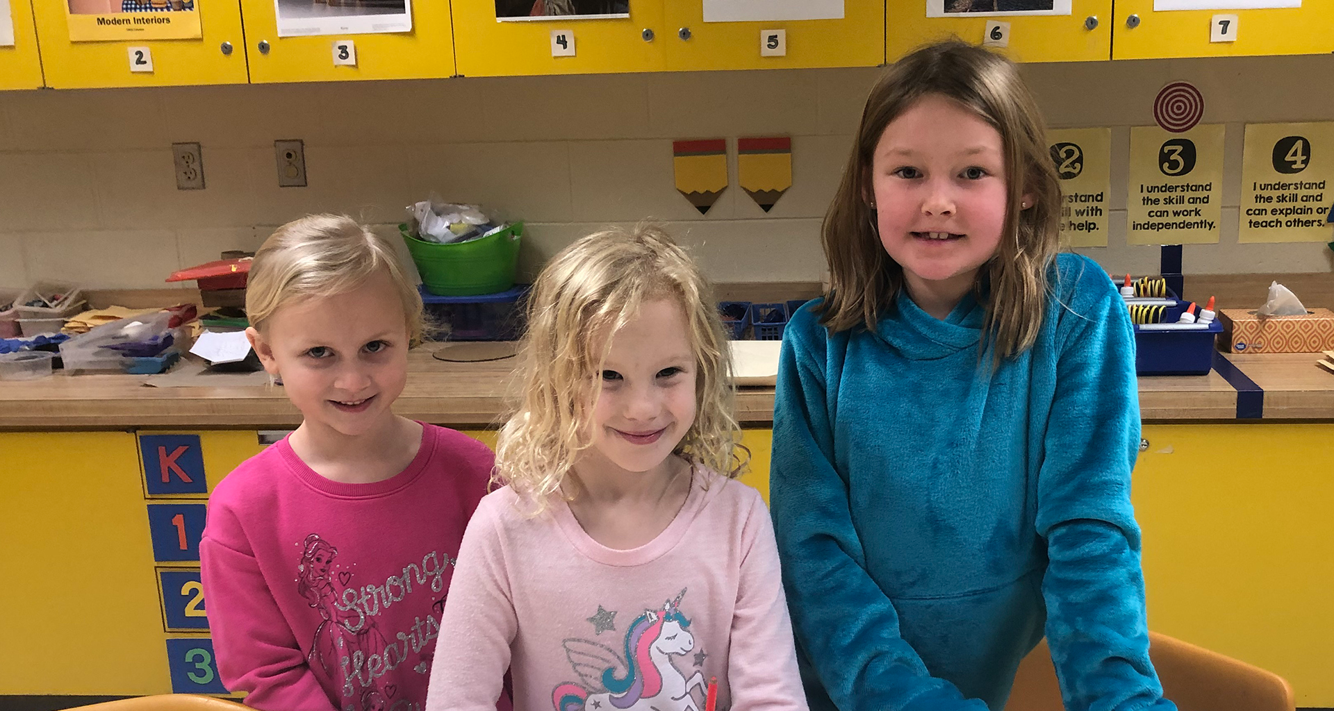 Three students working at their table in the classroom.