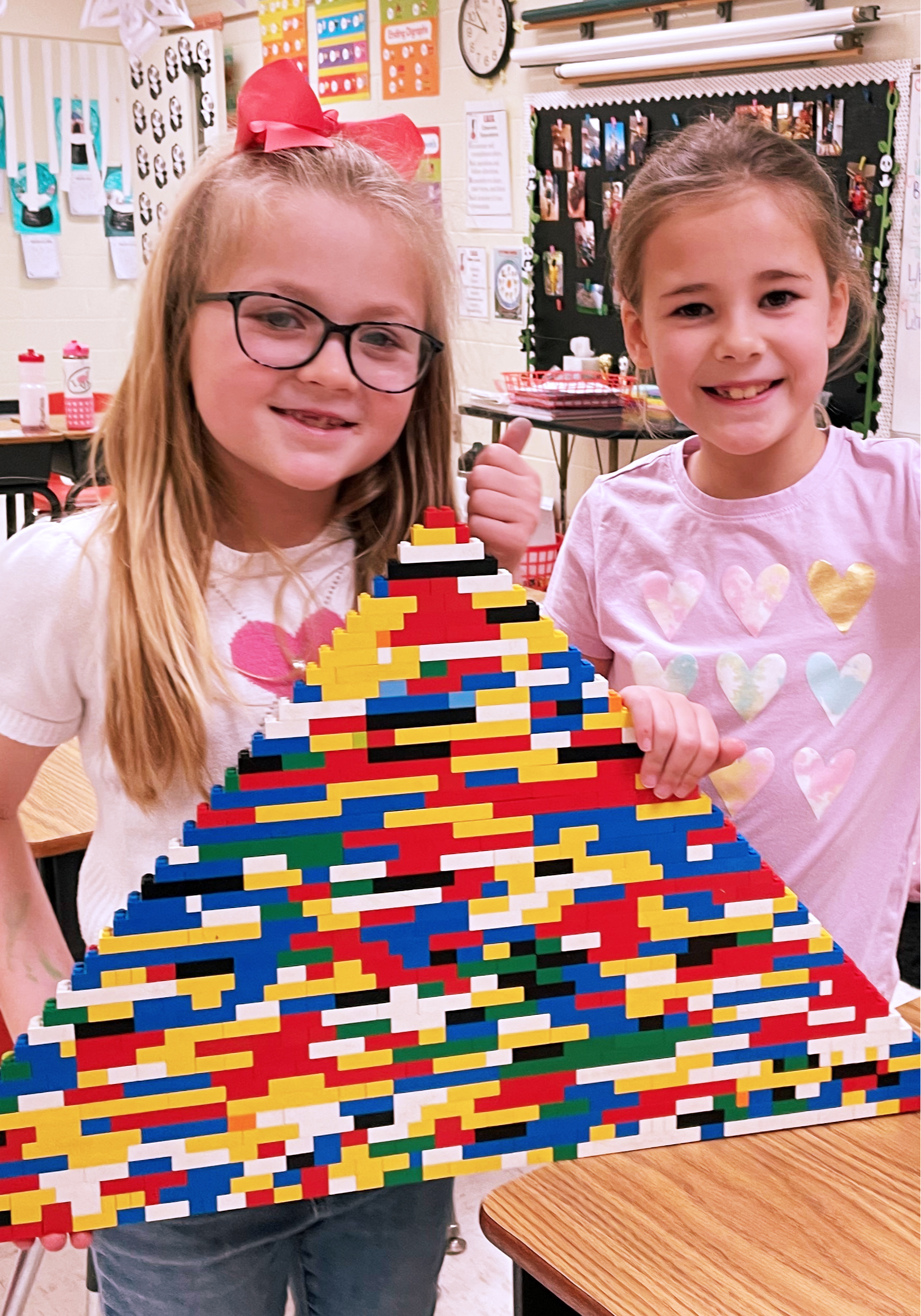 Two girls showing off their lego pyramid