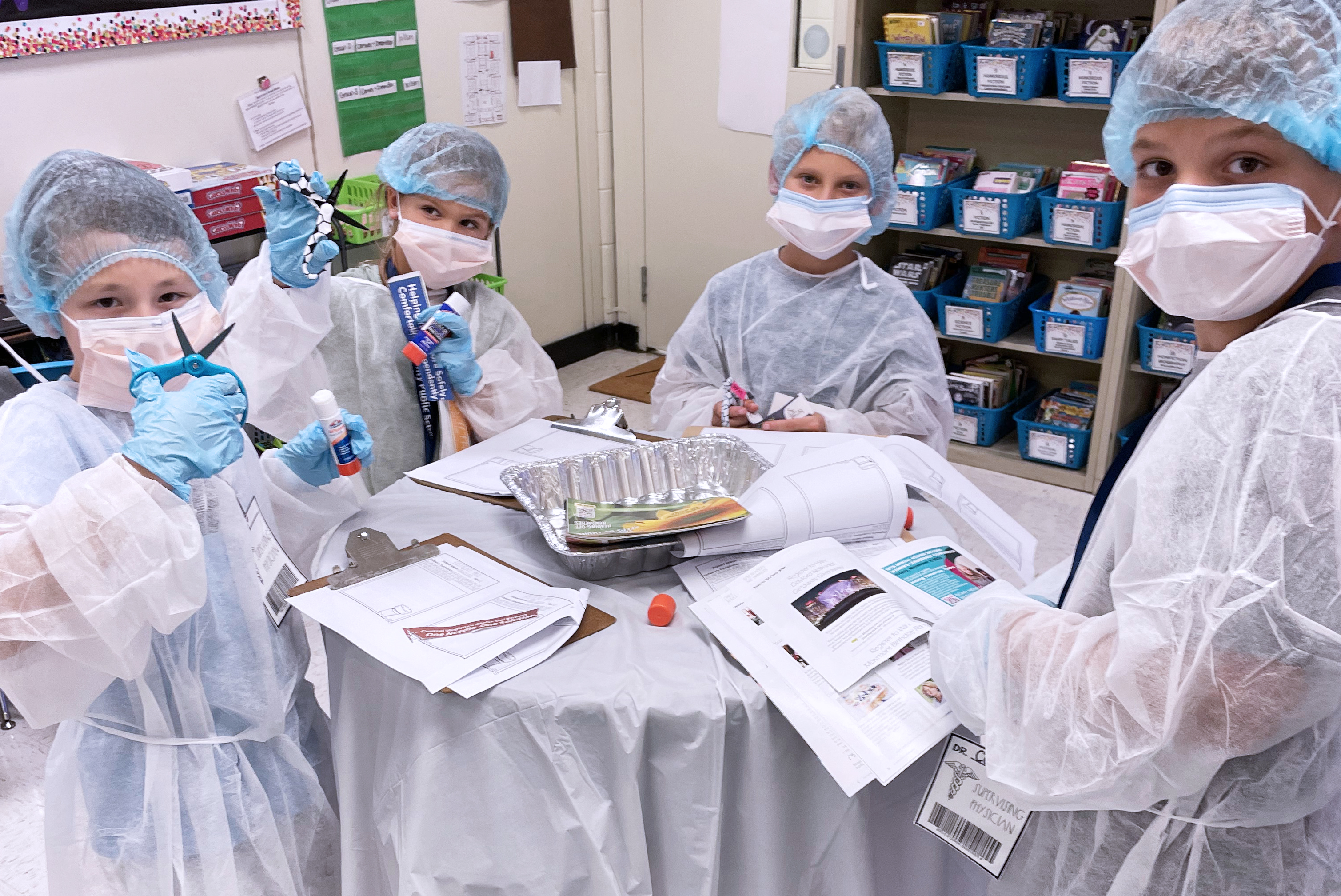 Students dressed like surgeons working together at a table.