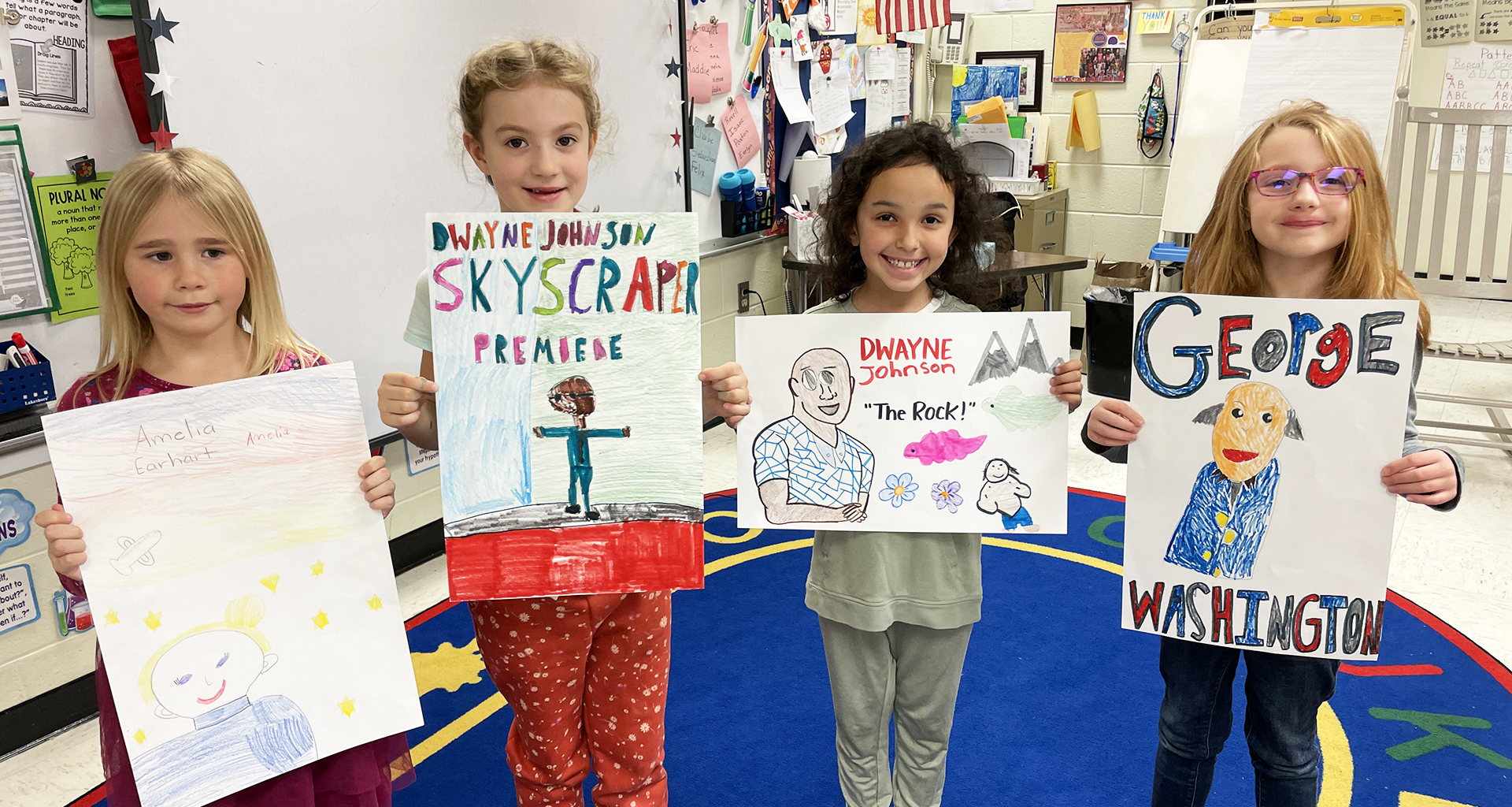 Four students show off their artwork.