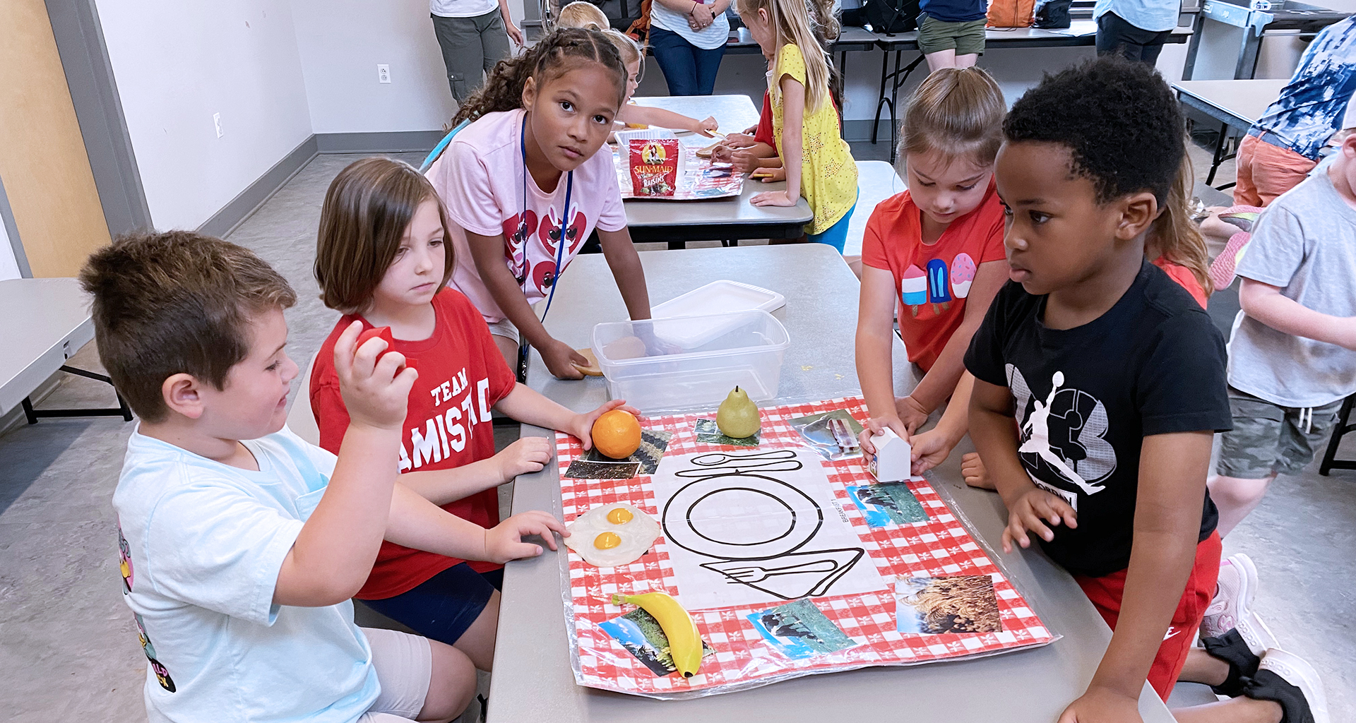 students sitting at a long table learning about the food groups.