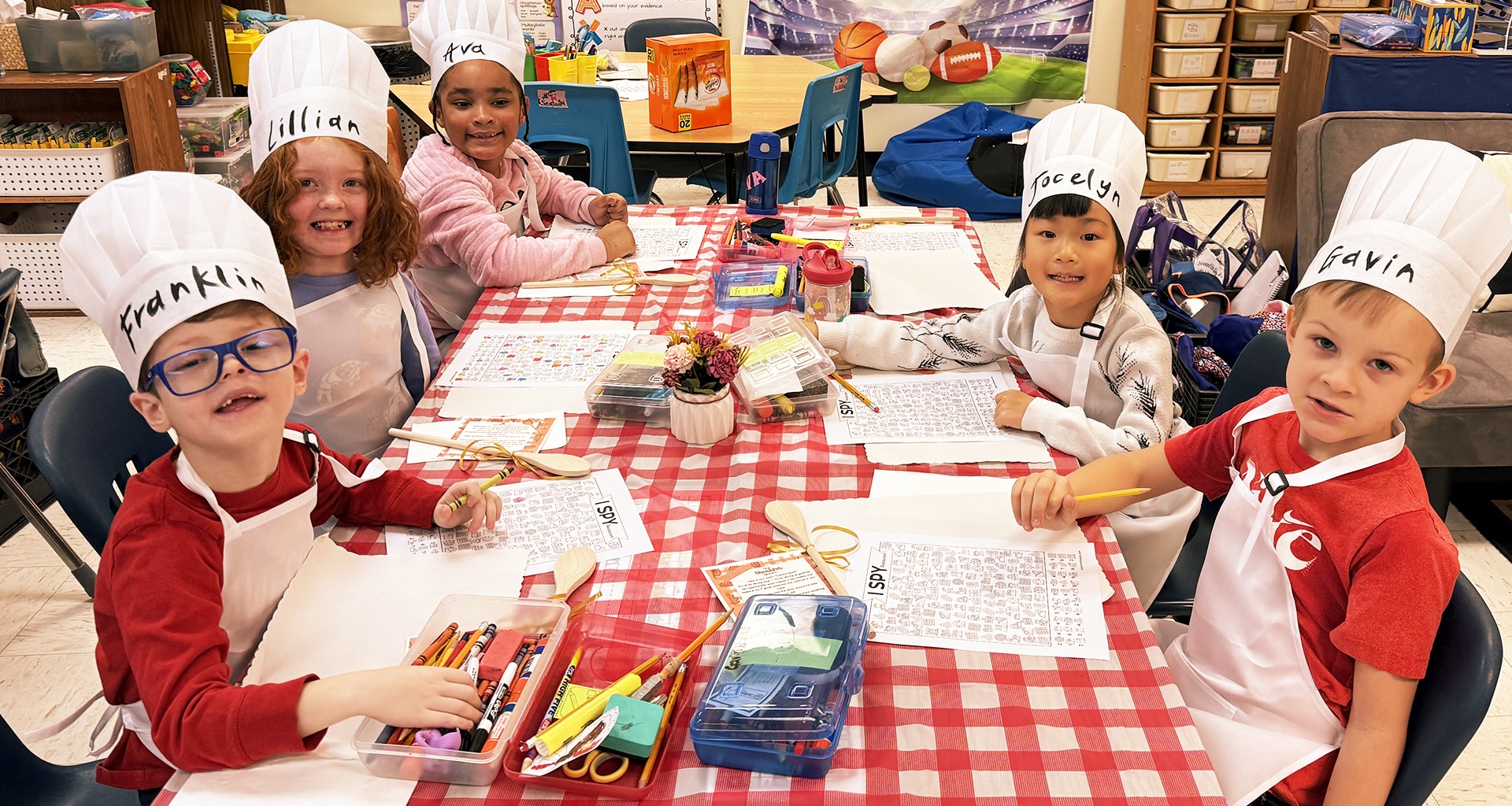 Students wearing chef hats working together at a table.