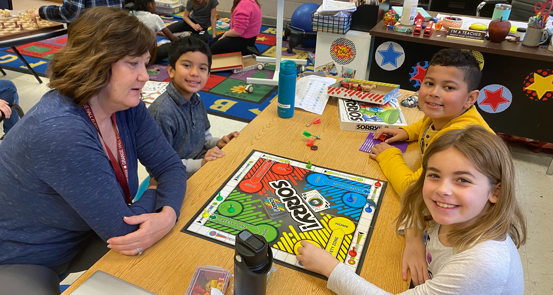Three students playing Sorry with their teacher.