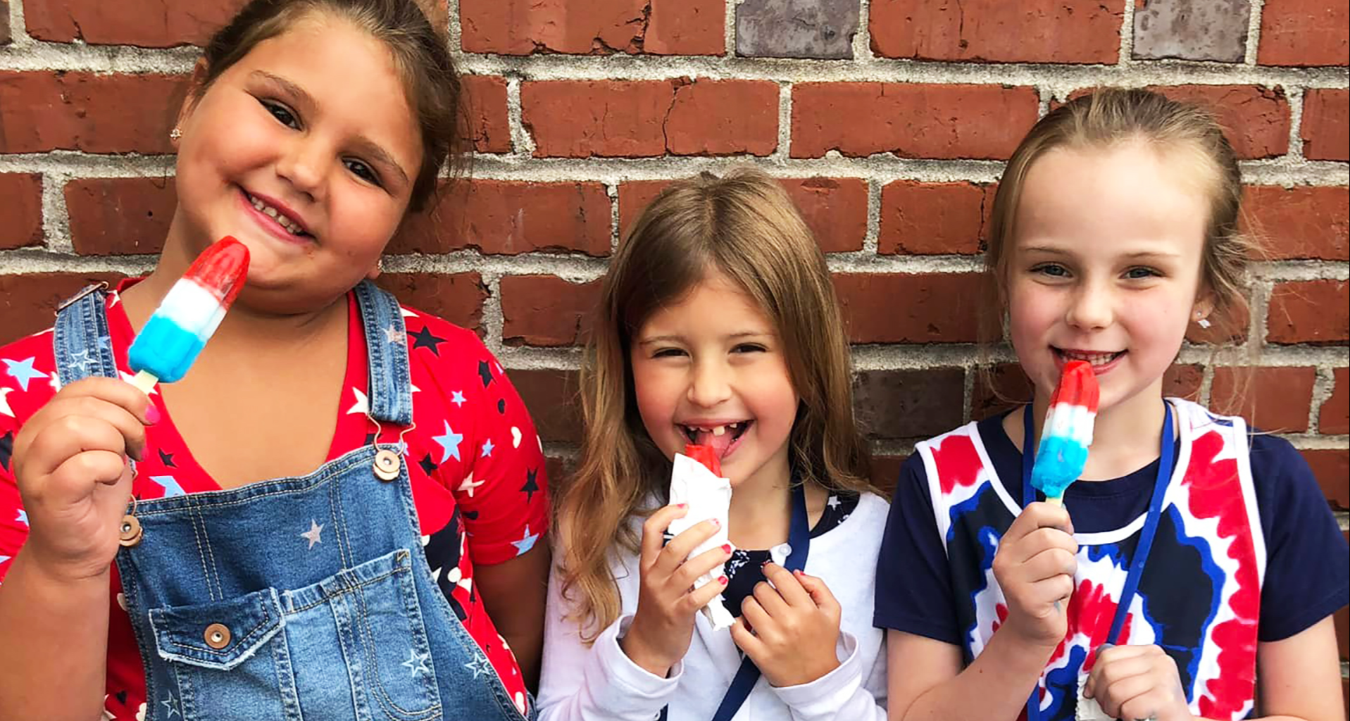 Three students eating a popsicle.