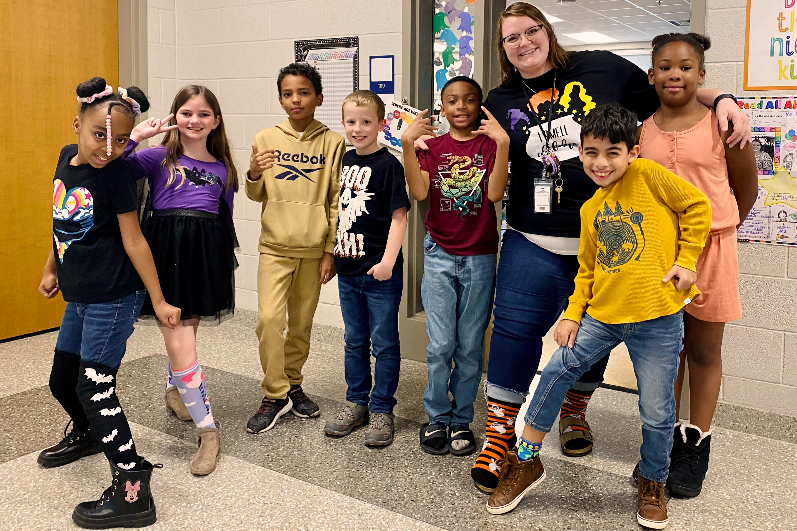 Group of students with their teacher being silly in the hallway.