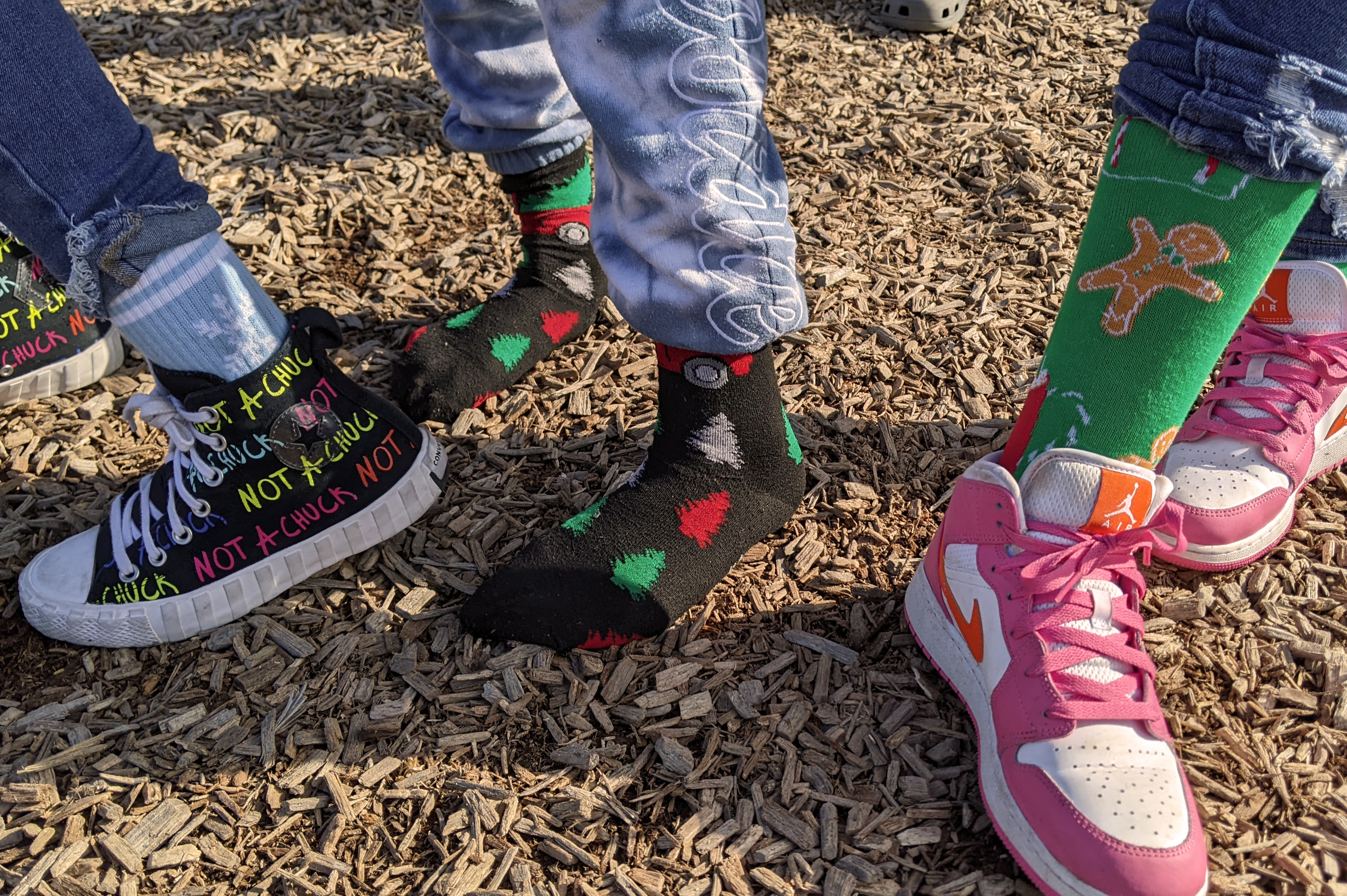 Three students showing their silly socks and shoes.