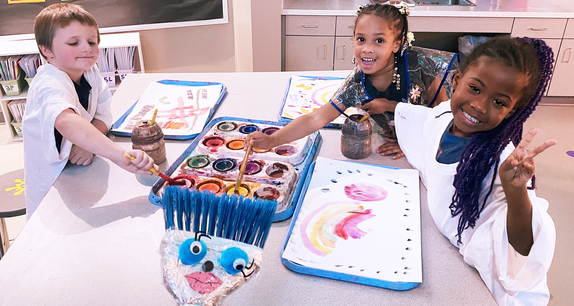 Three students in art class posing for a photo.