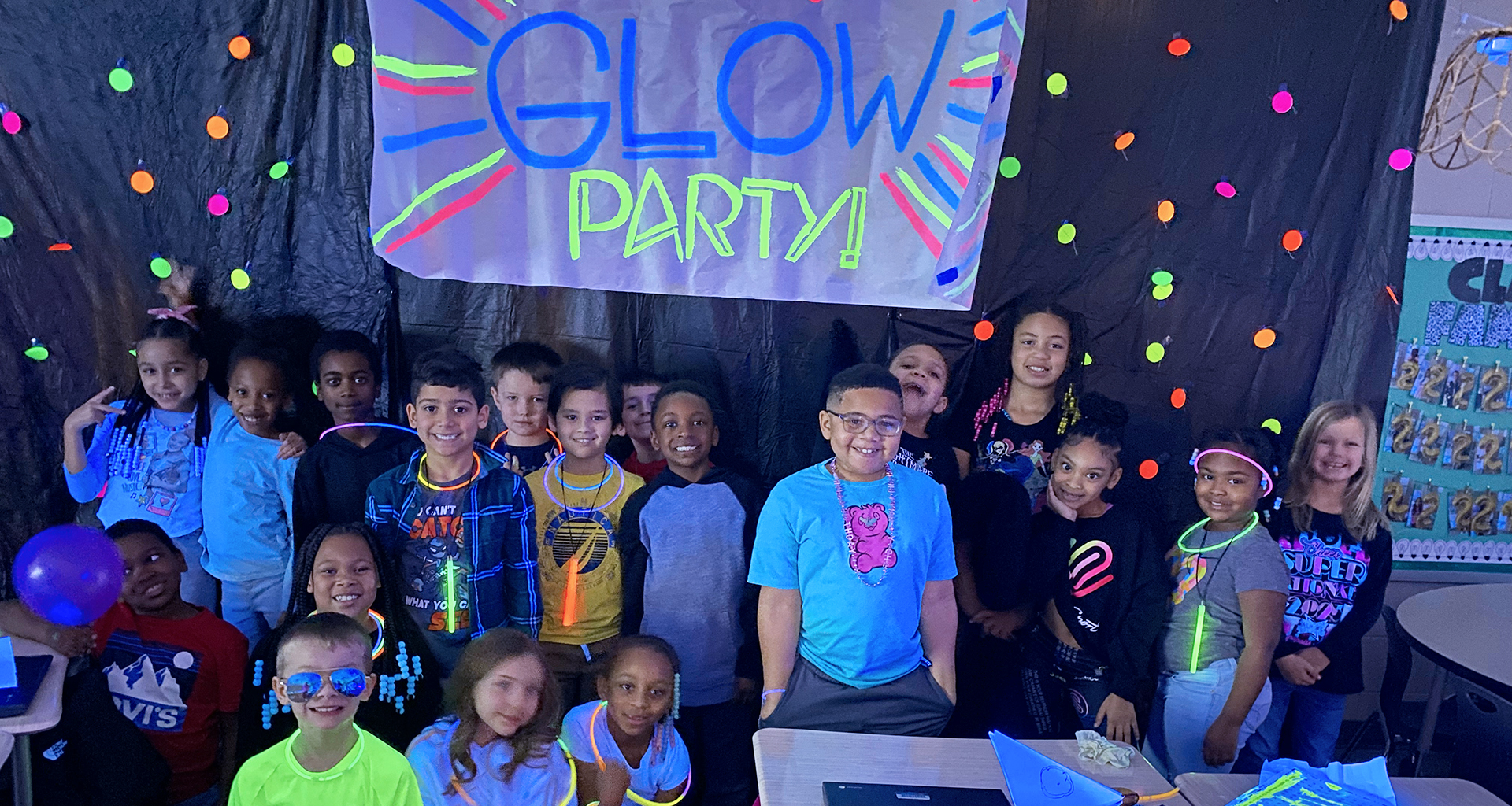 Students pose for a photo with the lights out and wearing their glow in the dark clothing and jewelry for their glow party.