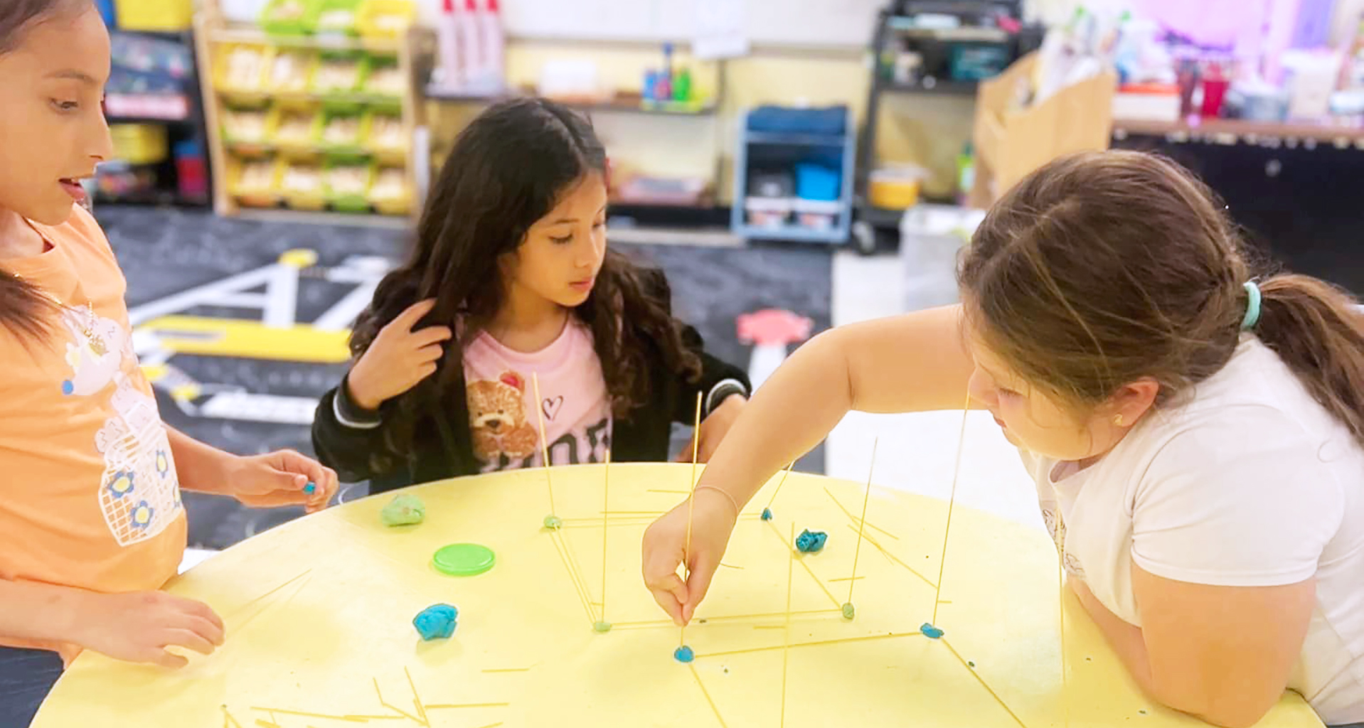 Three students building something at a table