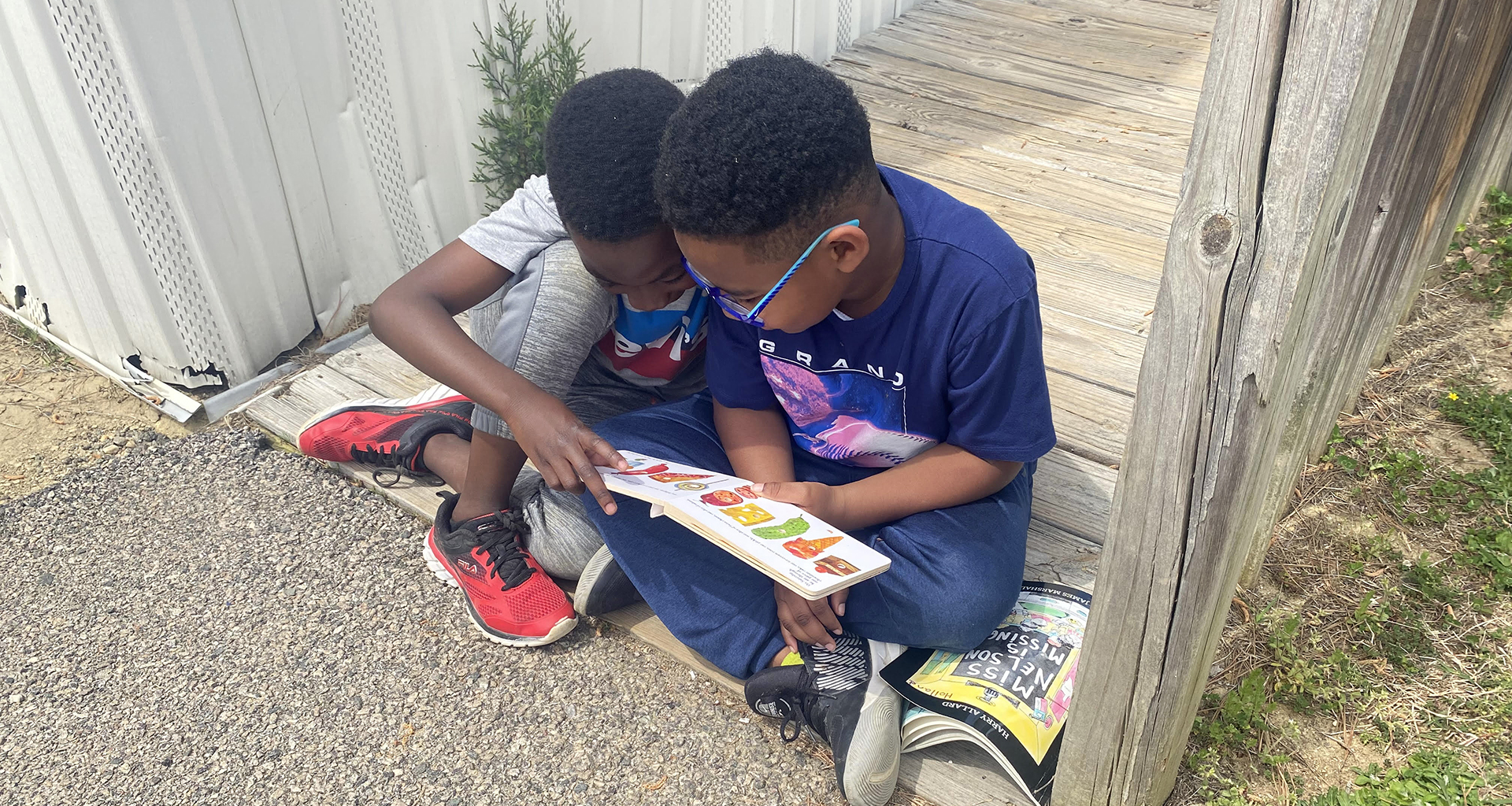 Two students sitting outside reading.