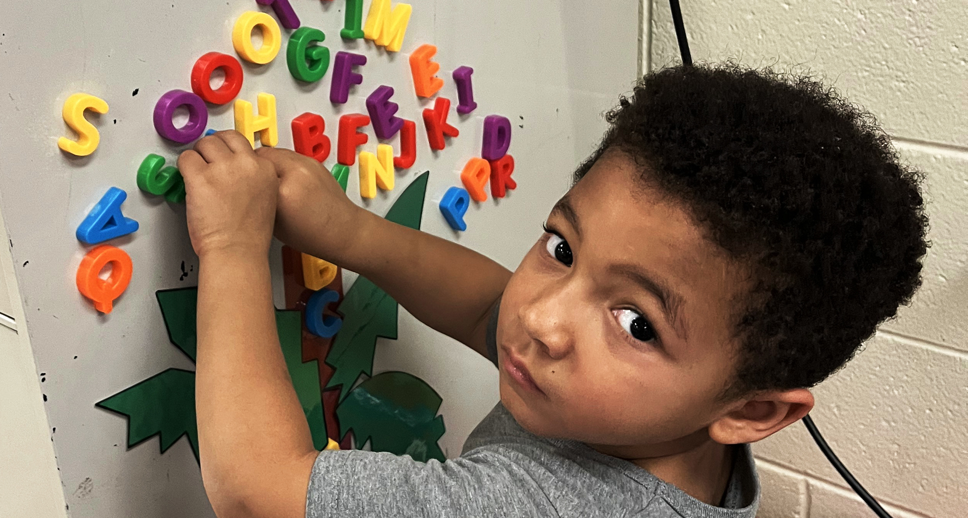 Young student playing with alphabet magnets.