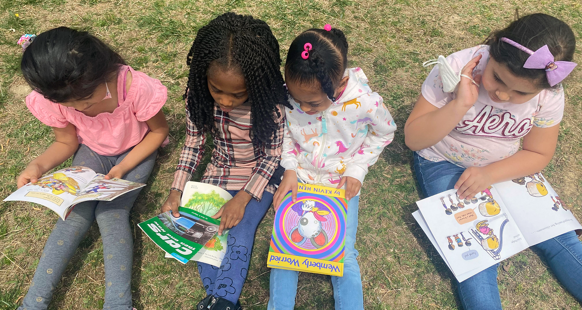 Four students on the grass reading their books