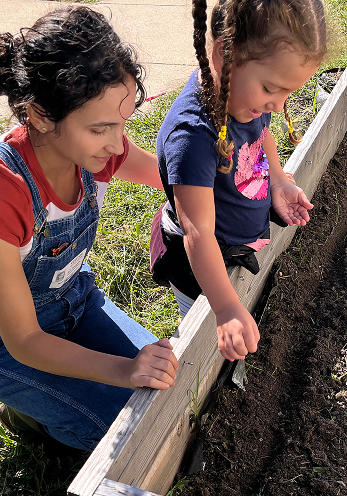 Teacher helps student plant seeds.