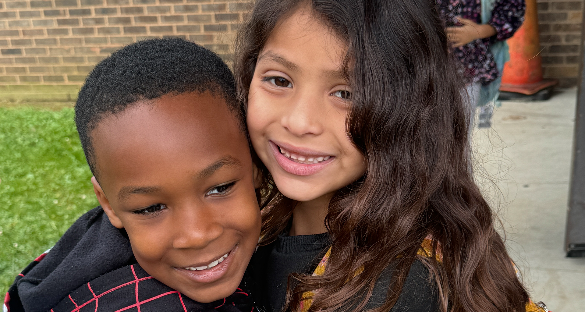 Two students hug and pose for a photo