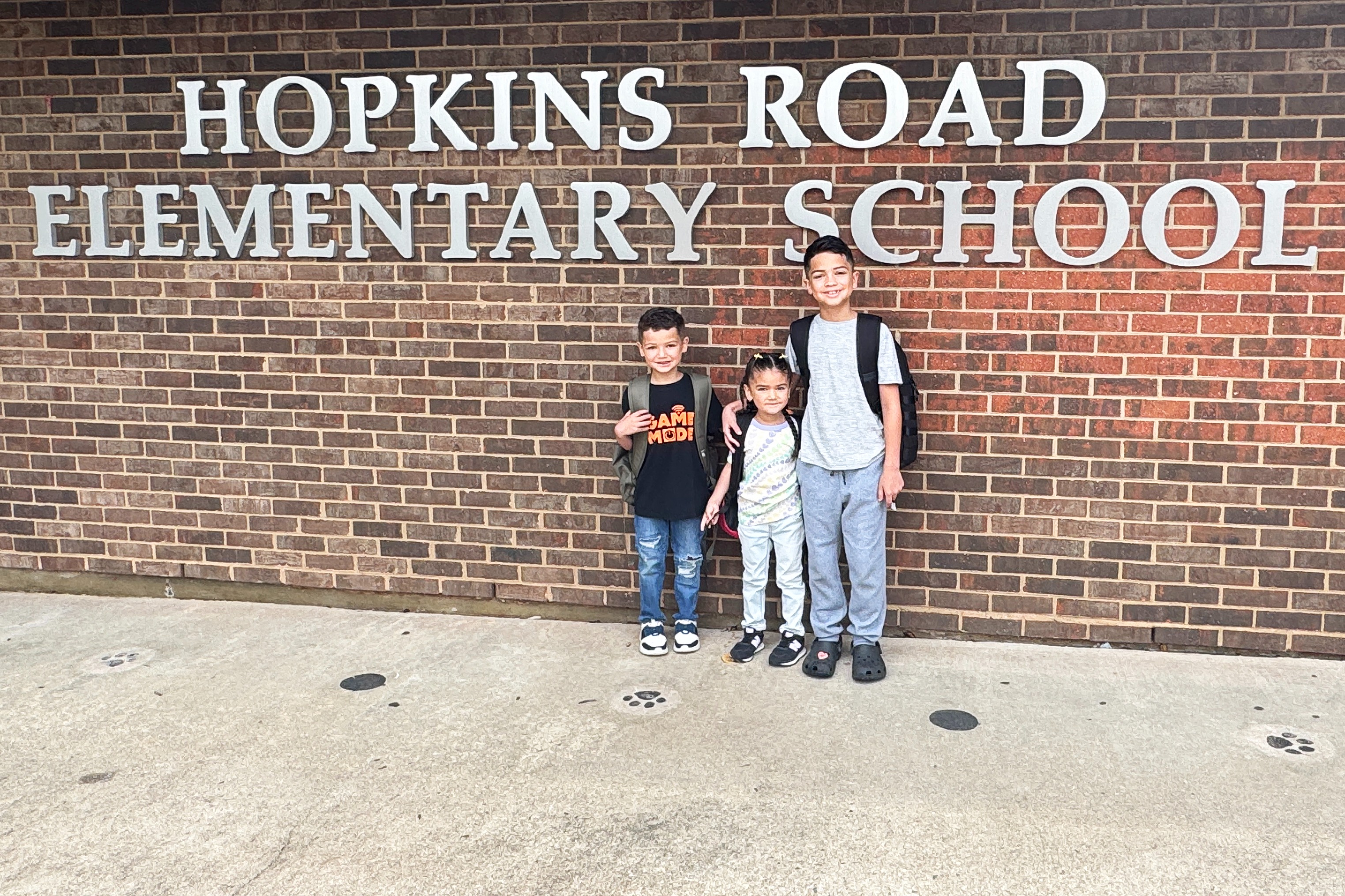 three students pose under school sign