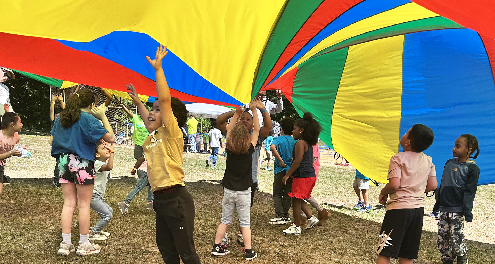 Students jumping under a giant rainbow tent