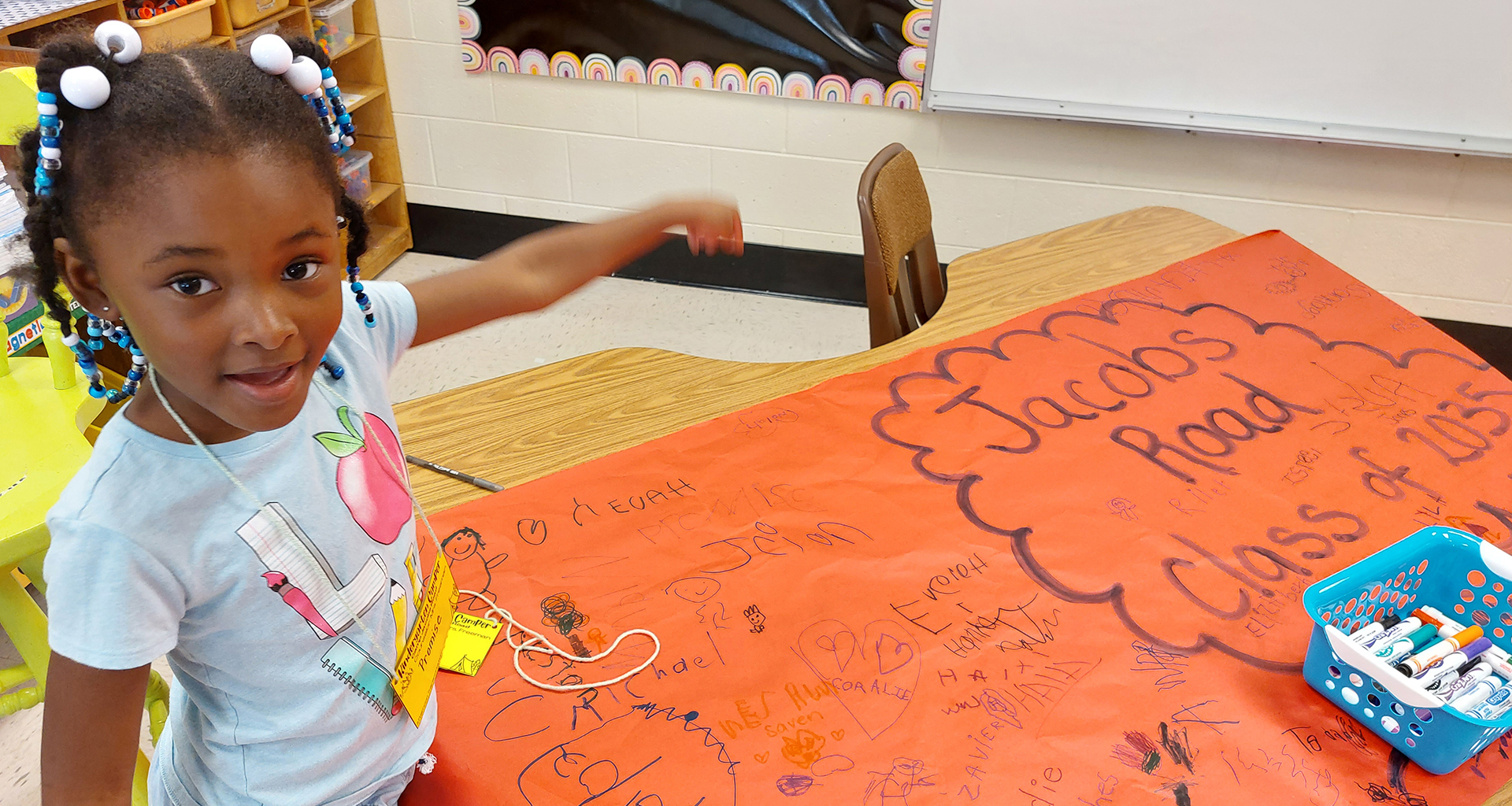 A little girl is pointing at an orange poster
