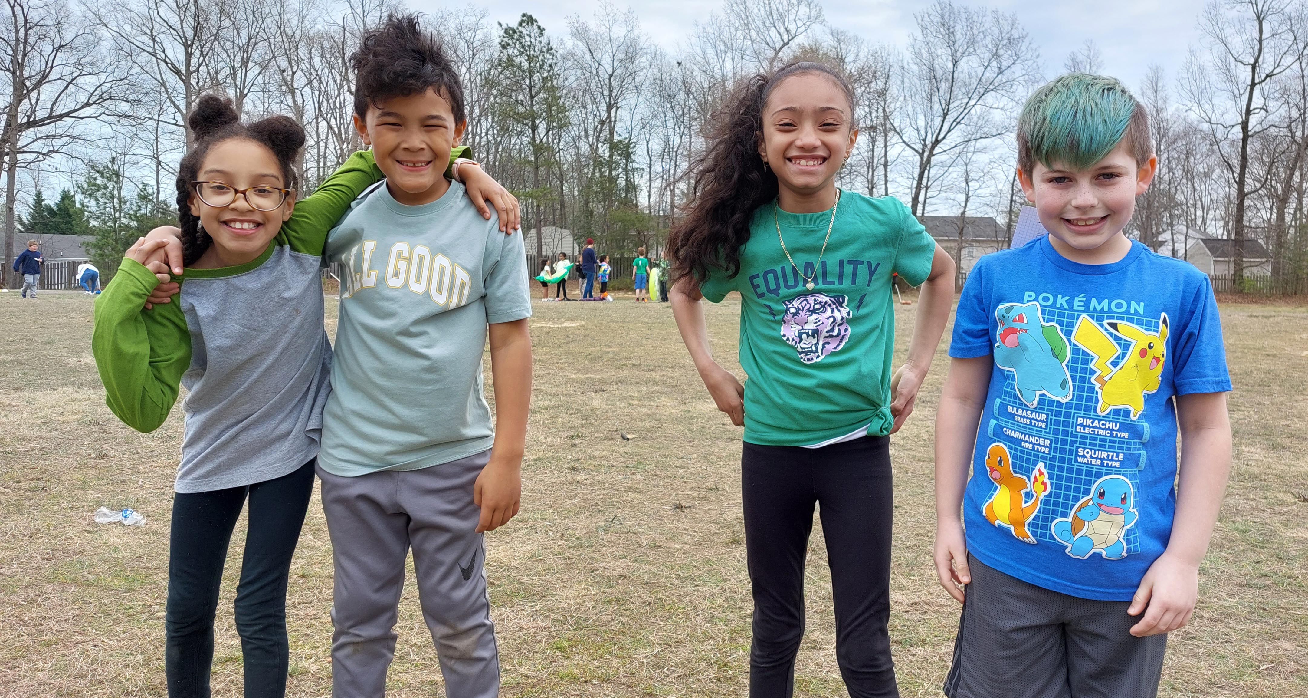 Four students smiling outside on the school field
