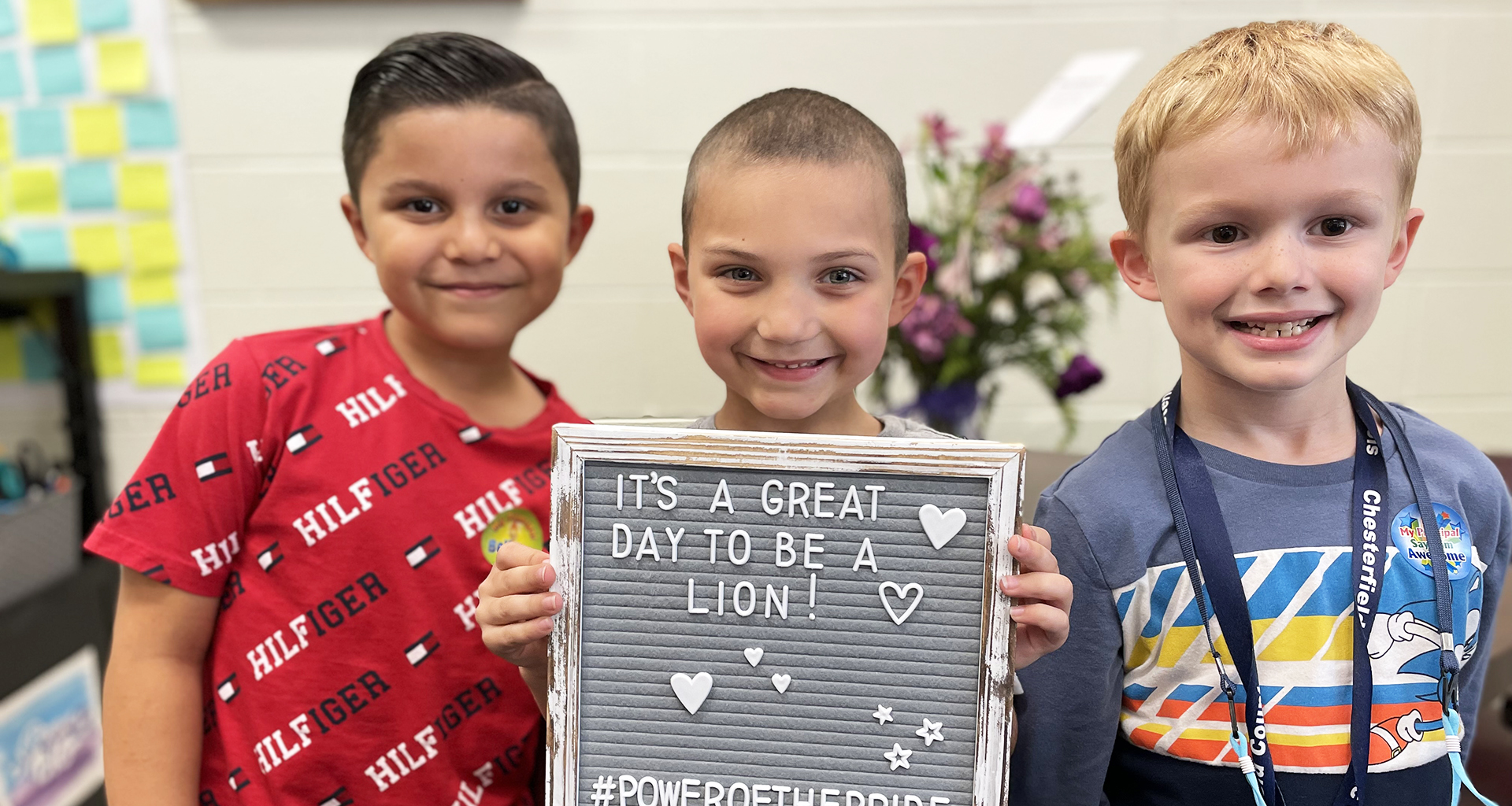 Three boys holding a sign that says it is great to be a lion!