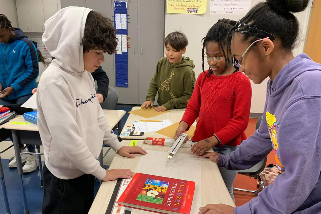 Three students testing out a scientific instrument in class