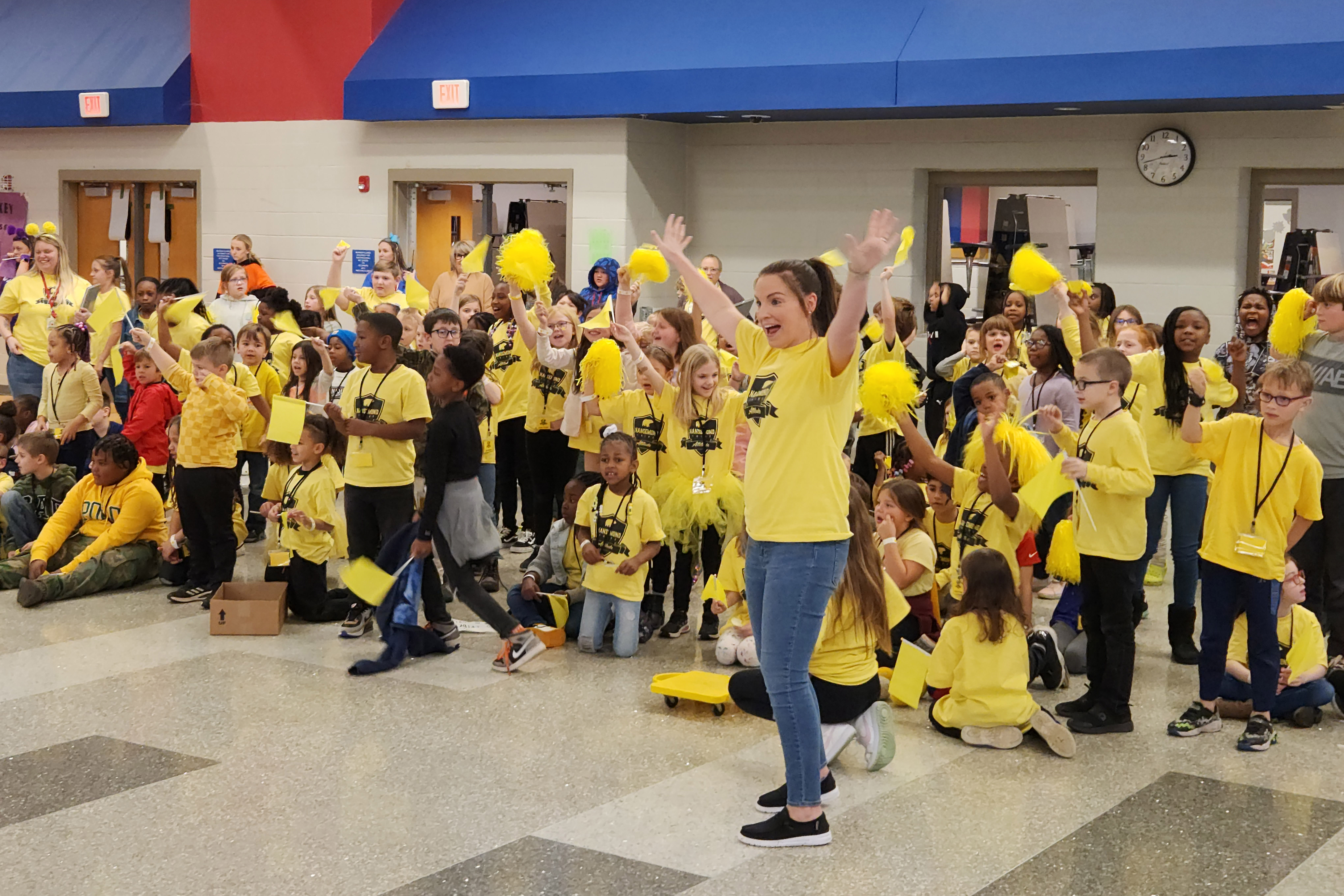 A large group of students wearing yellow cheering in the cafeteria