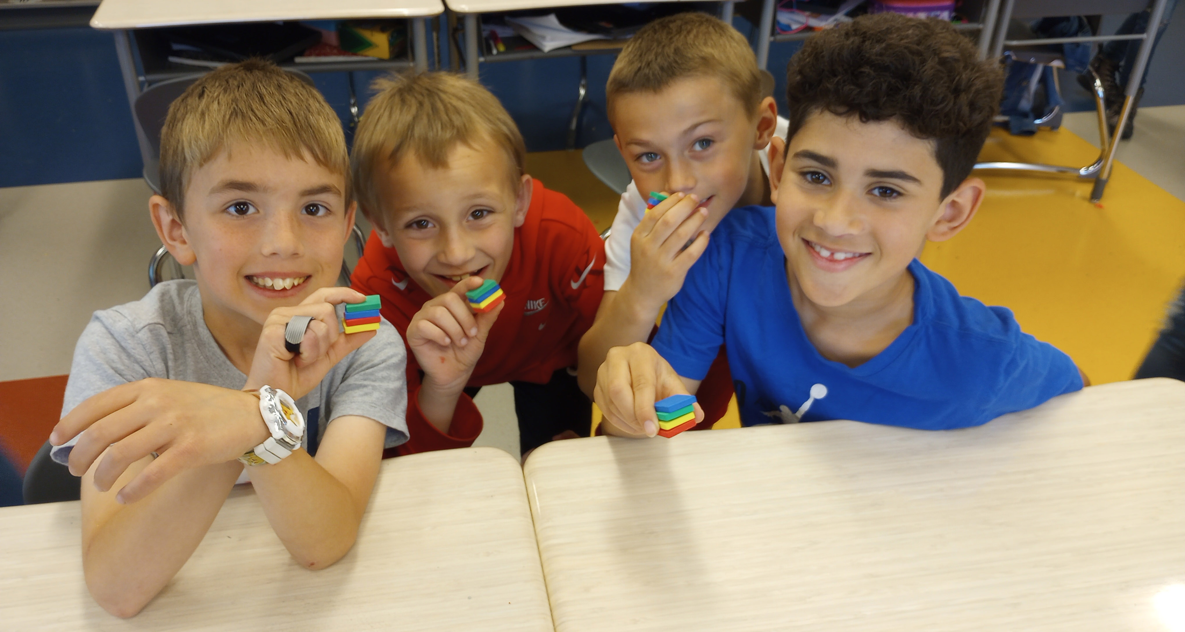 Four boys in class holding plastic squares in their hands