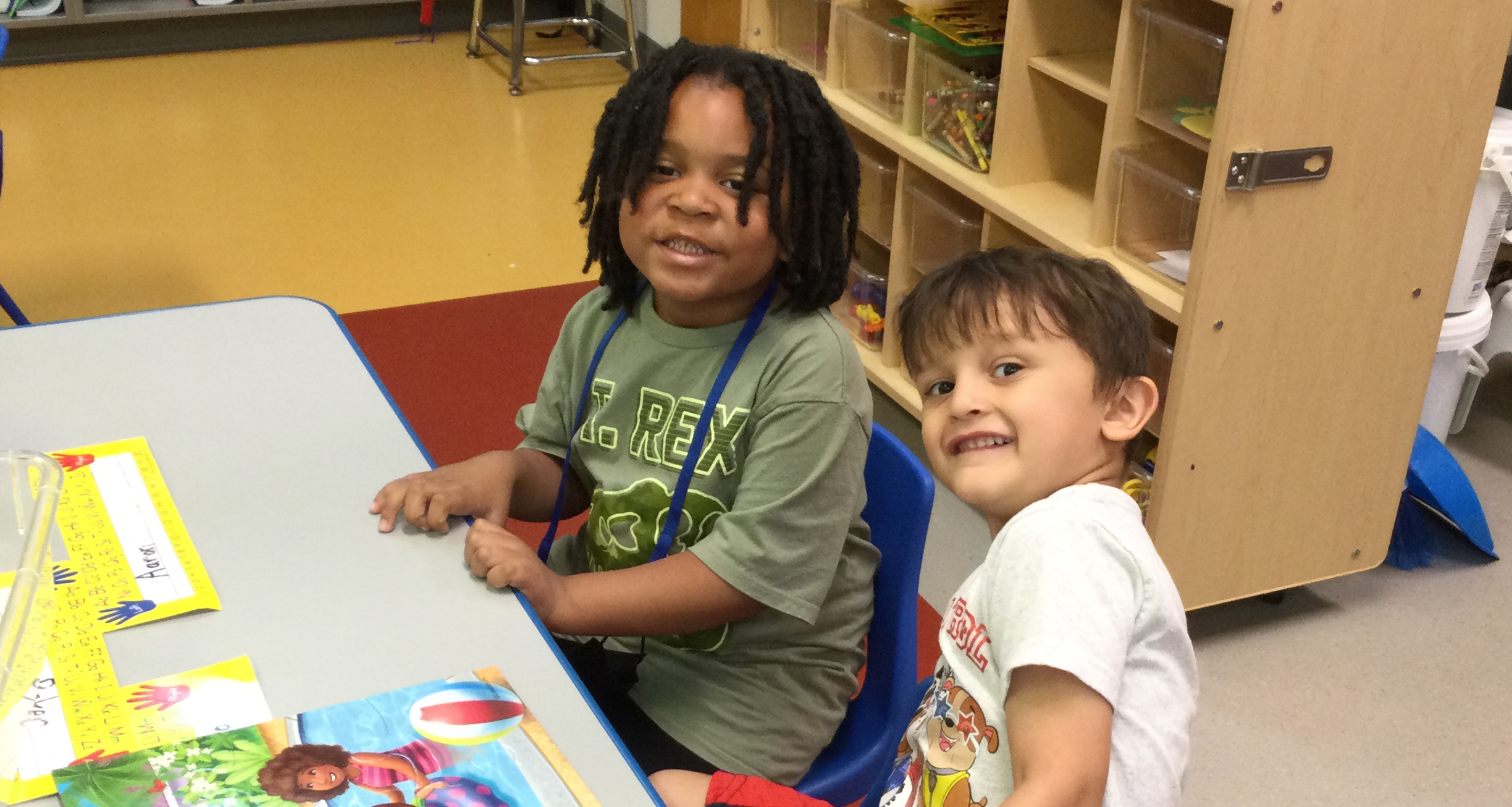 Two prekindergartners smile for a photo in class