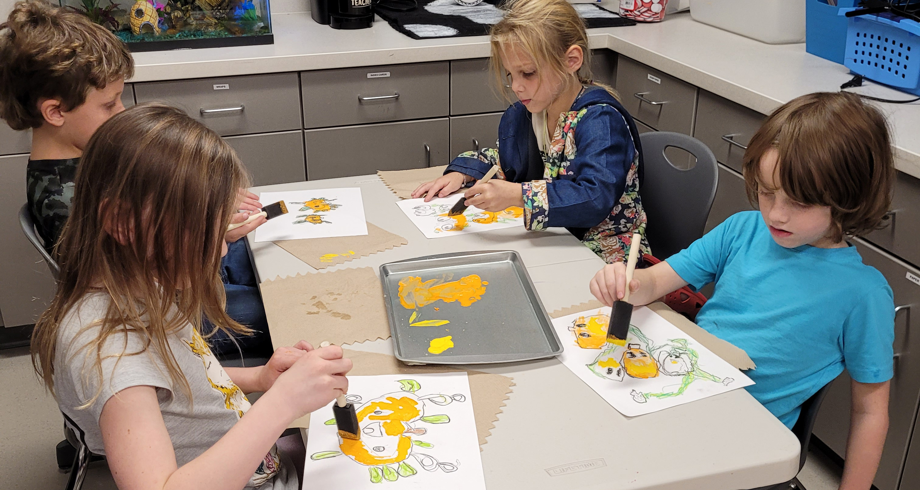 Four students painting a picture of a pumpkin