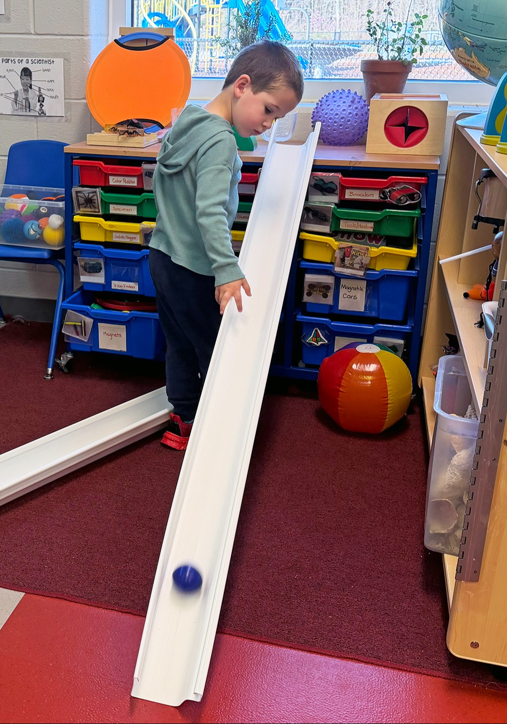 student rolling a ball down a track