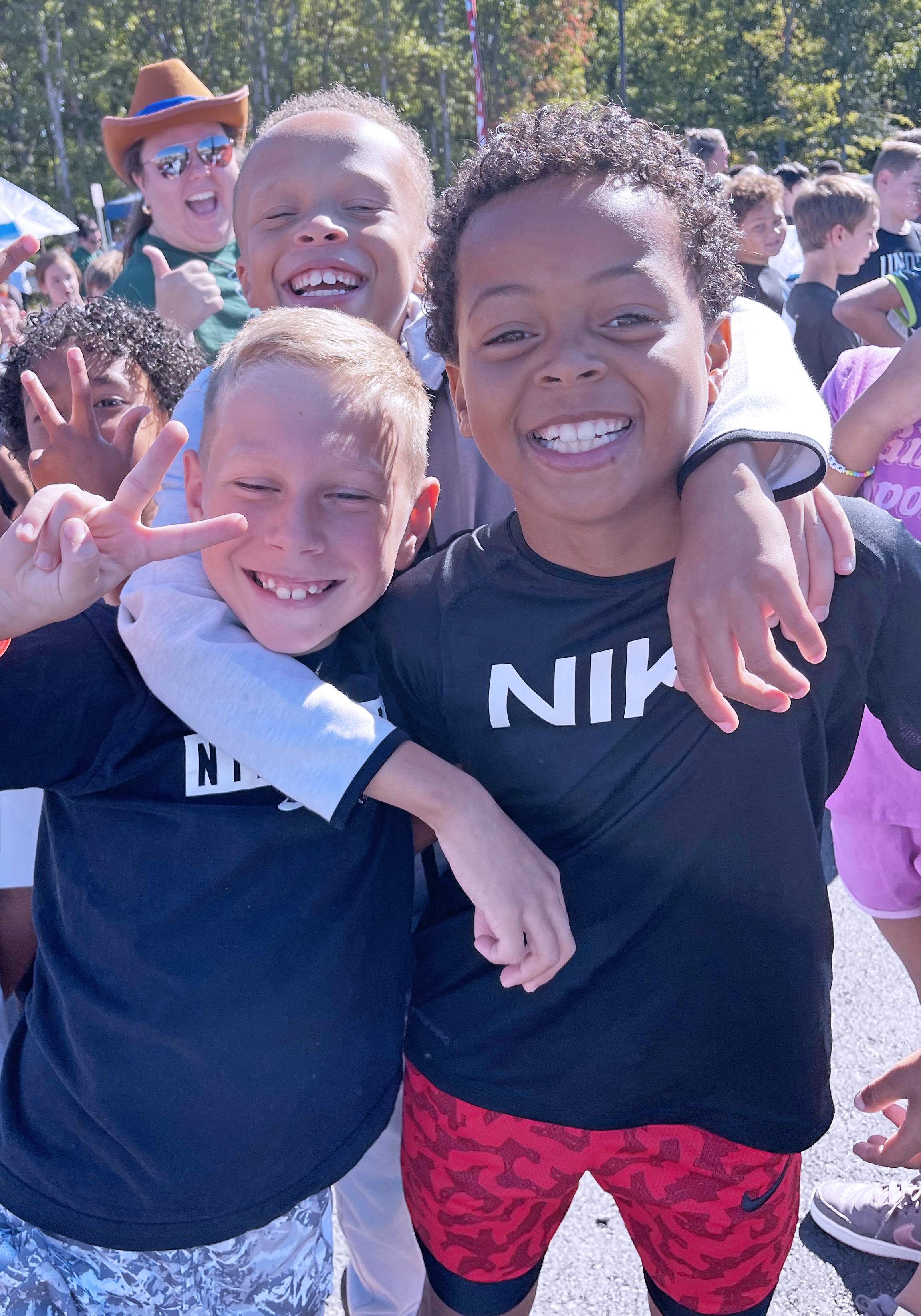 Three students hamming it up outside in a large crowd.