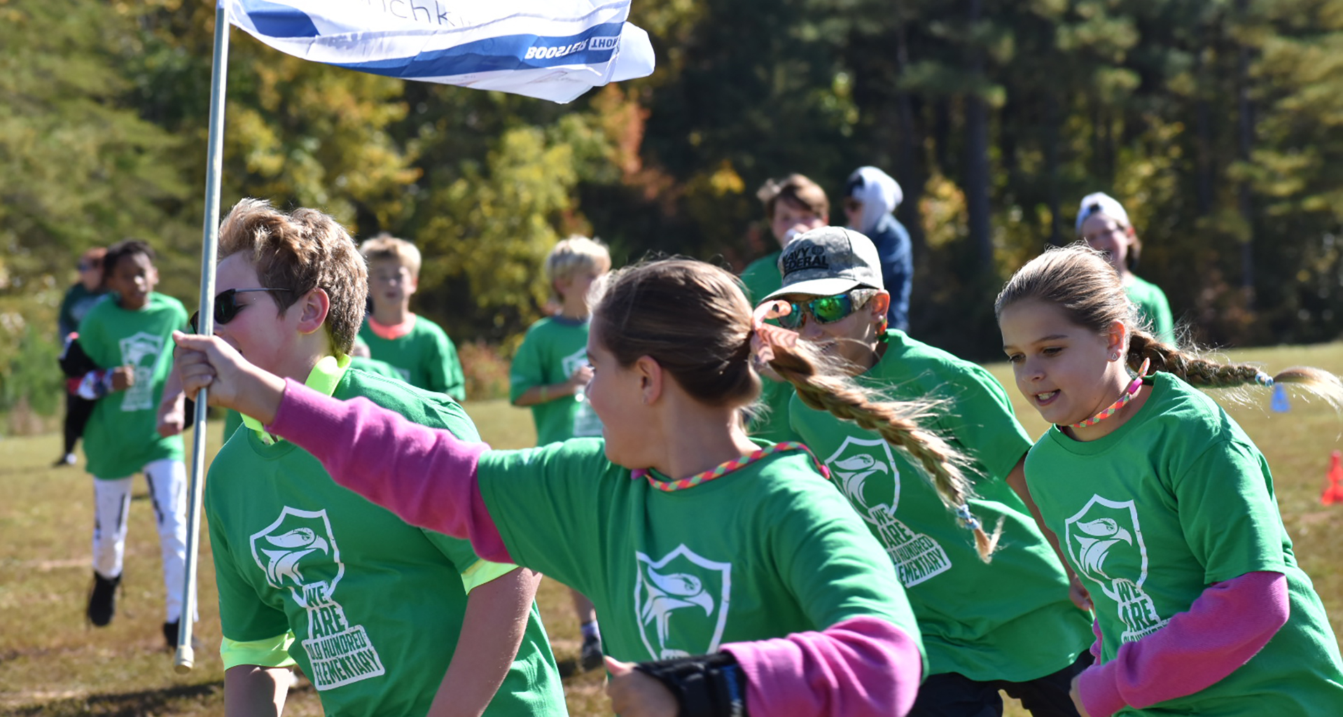 Students running with a flag all dressed in school spiritwear