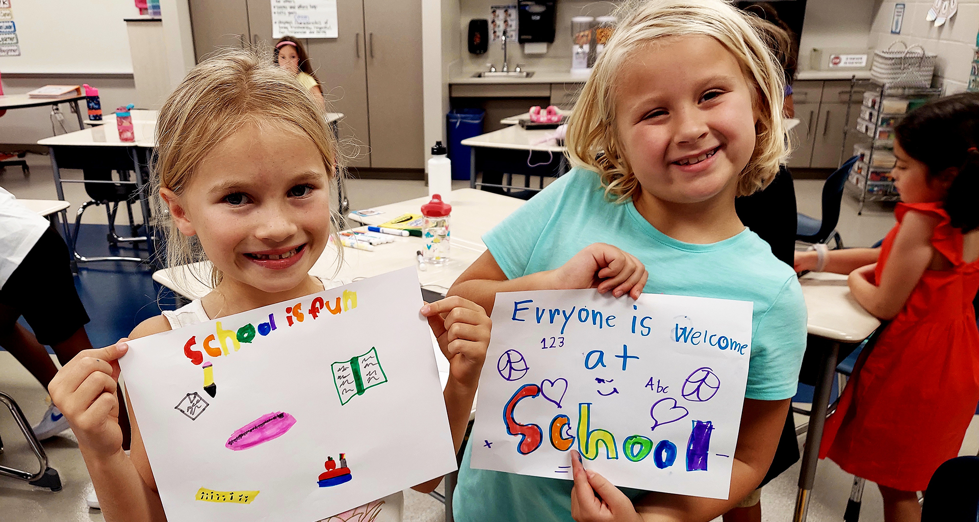 Two female students hold up their artwork.