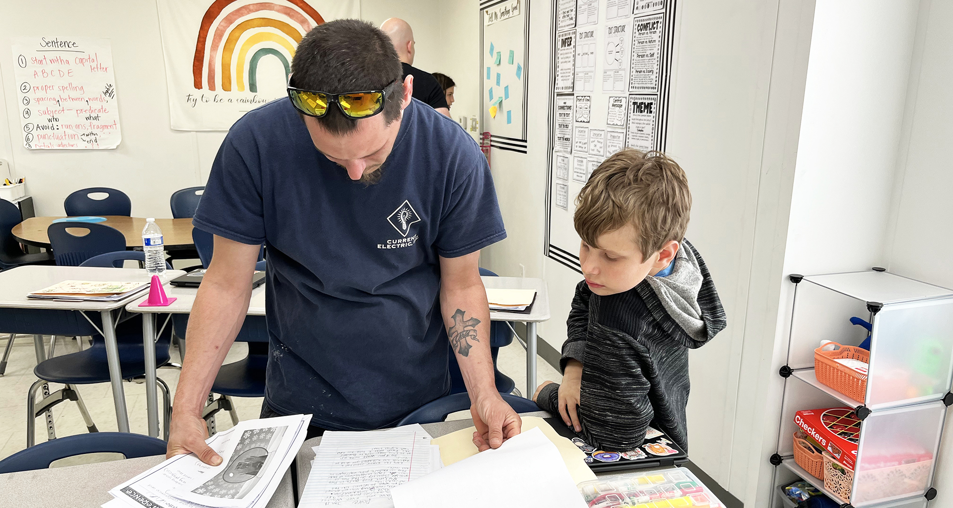 Student and adult looking at assignment on the desk.